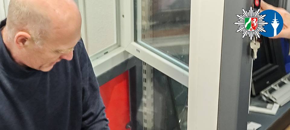 Ein Polizist demonstriert mit Einbruchswerkzeug, wie eingebrochen wird. Er hebelt ein Fenster auf.