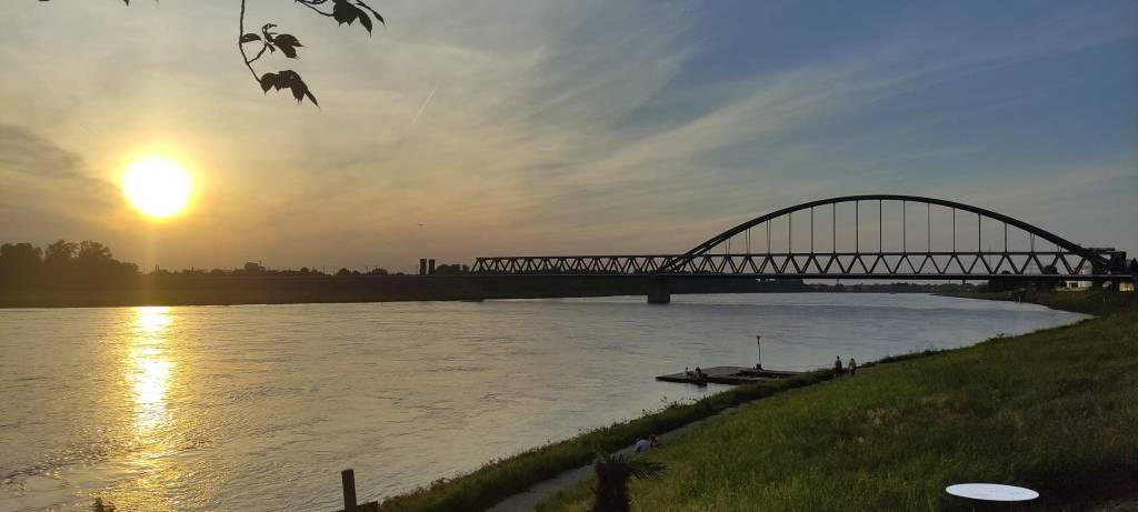 Die Eisenbahnbrücke in Hamm im Sonnenuntergang. Die Sonne spielgelt sich im Rhein wider.