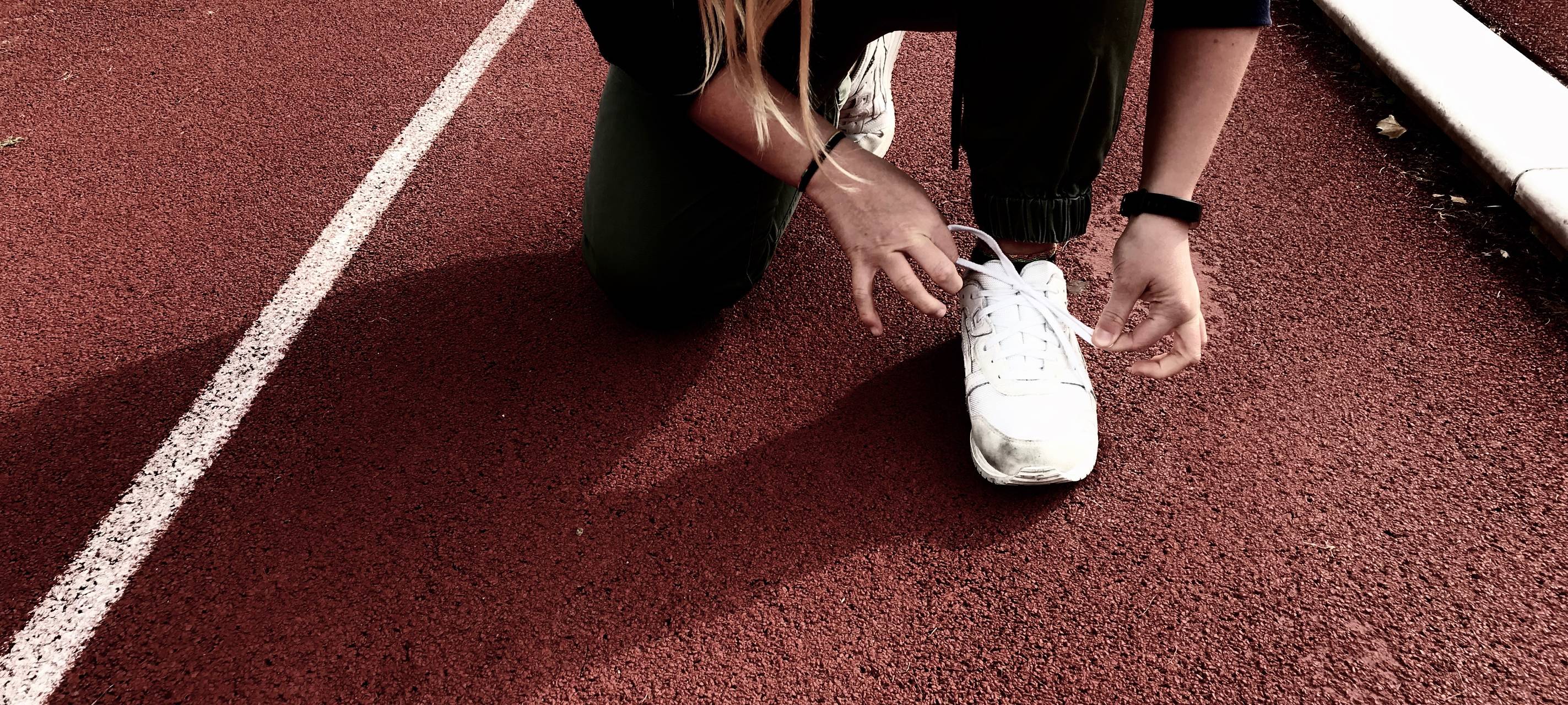 Sportler schnürt sich seinen weißen Turnschuh zum Laufen.