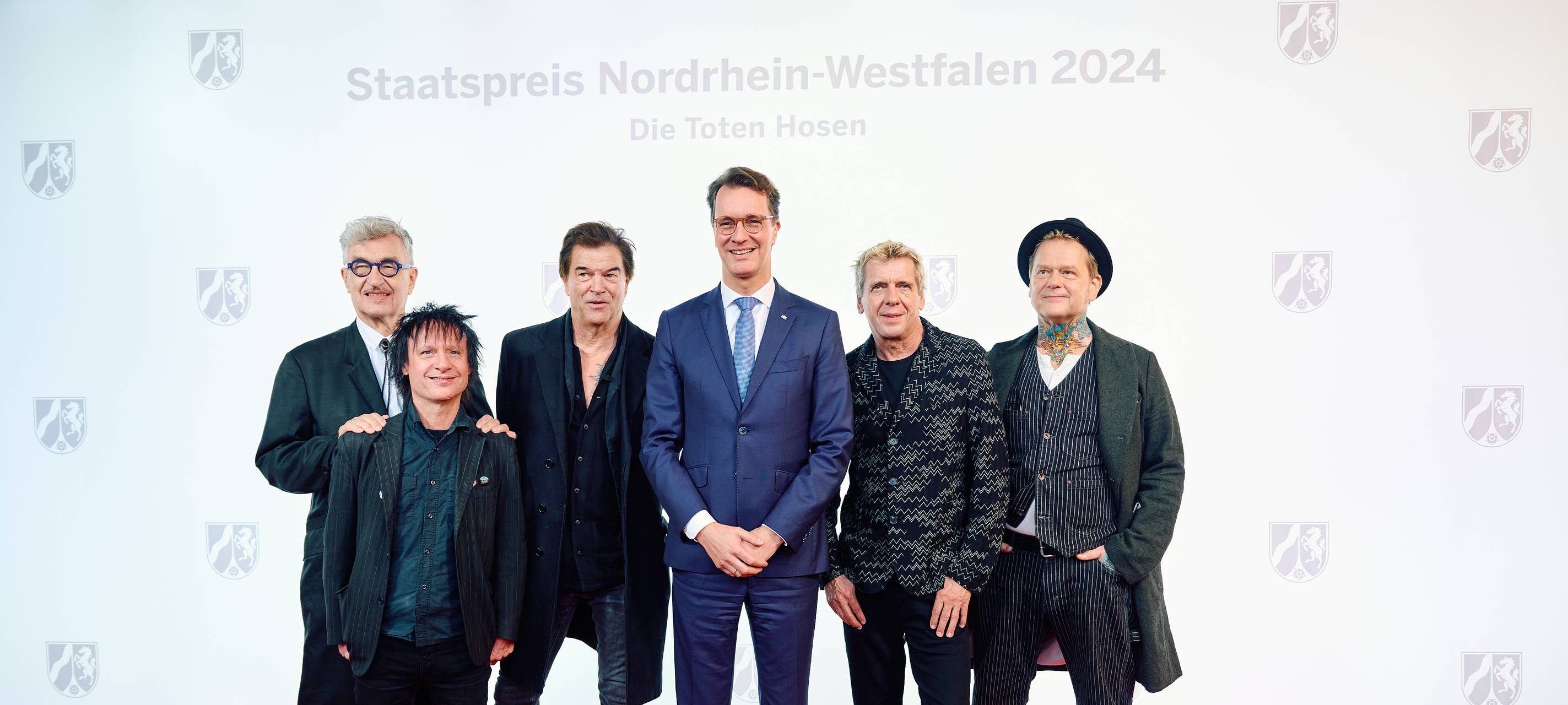 Die Toten Hosen und Ministerpräsident Hendrik Wüst stehen bei der Preisverleihung vom NRW-Staatspreis auf dem Roten Teppich.