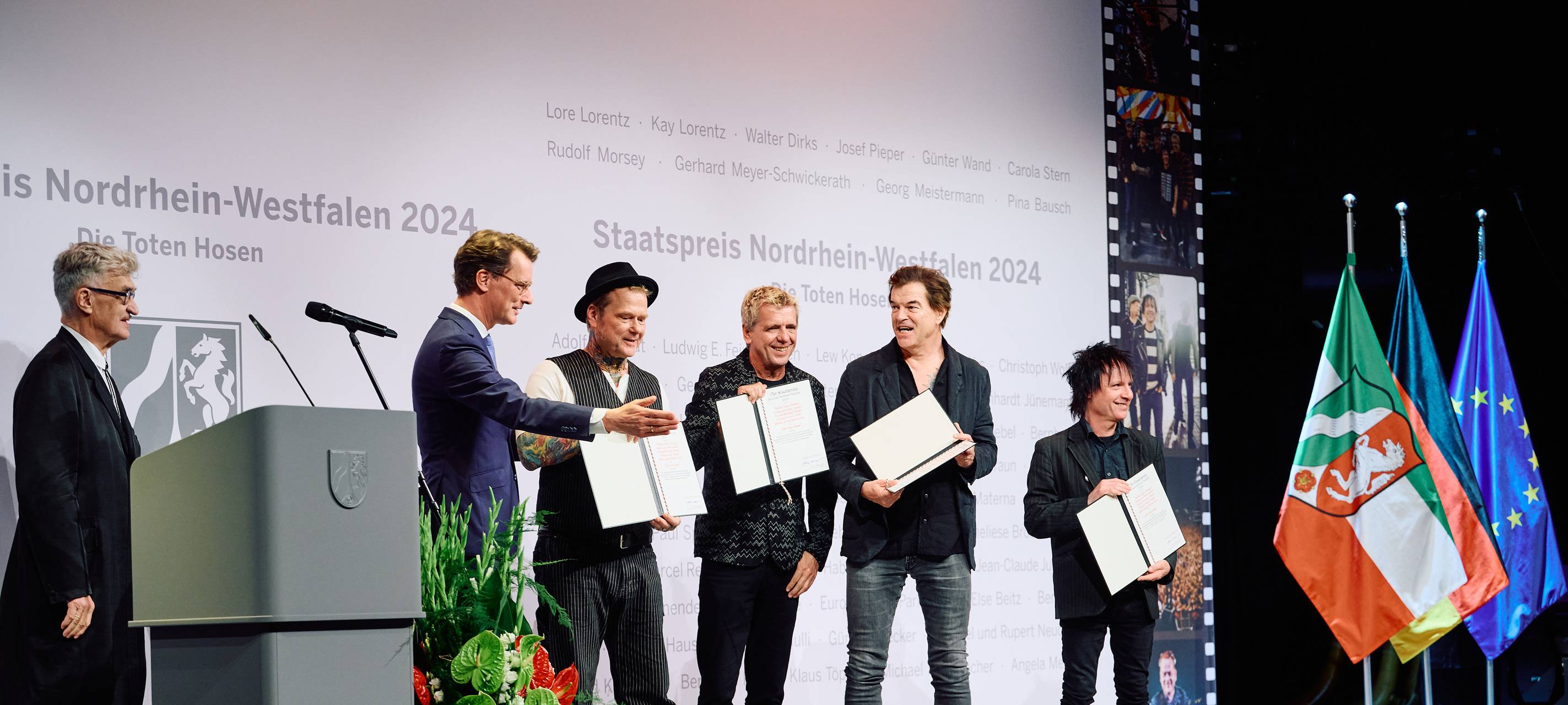 NRW-Ministerpräsident Hendrik Wüst verleiht den Toten Hosen den NRW-Staatspreis. Auch der Regisseur Wim Wenders ist auf der Bühne. Er hat die Laudatio gehalten.