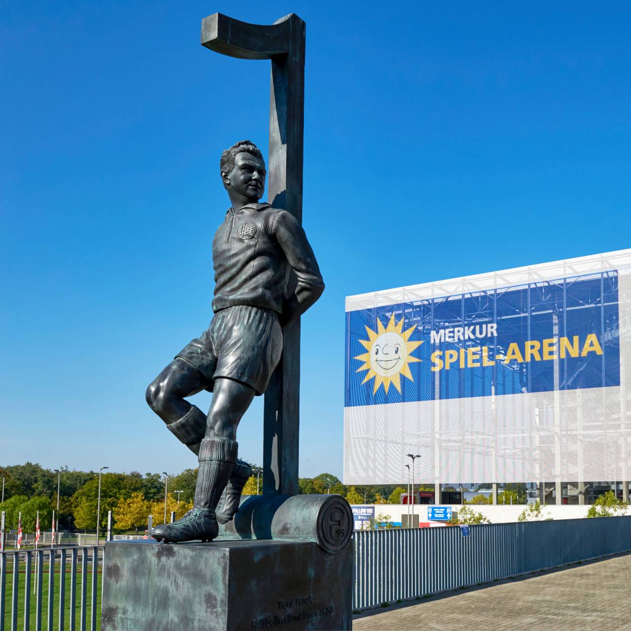 Die Merkur-Spiel-Arena im Hintergrund. Im Vordergrund steht das Toni-Turek-Denkmal auf dem Arena-Vorplatz.