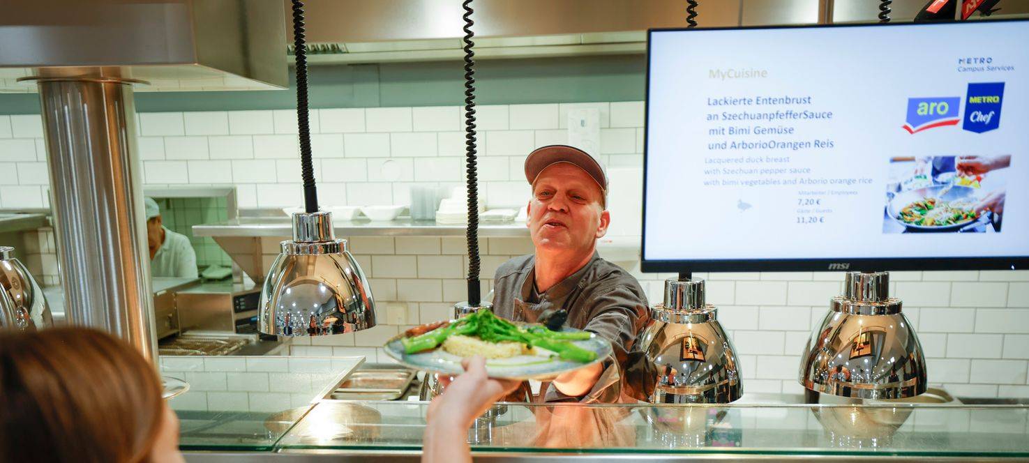 Ein Teilnehmer des "Housing First meets Gastro" Projekts gibt Essen in der Kantine aus