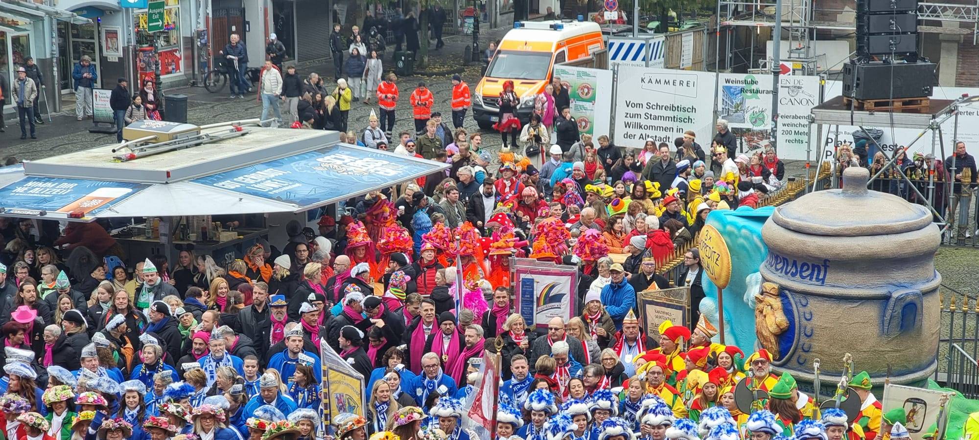Karnevalisten aus Düsseldorf warten gespannt auf dem Hoppeditz. Er steckt noch im Senftopf, der auf dem Marktplatz steht.