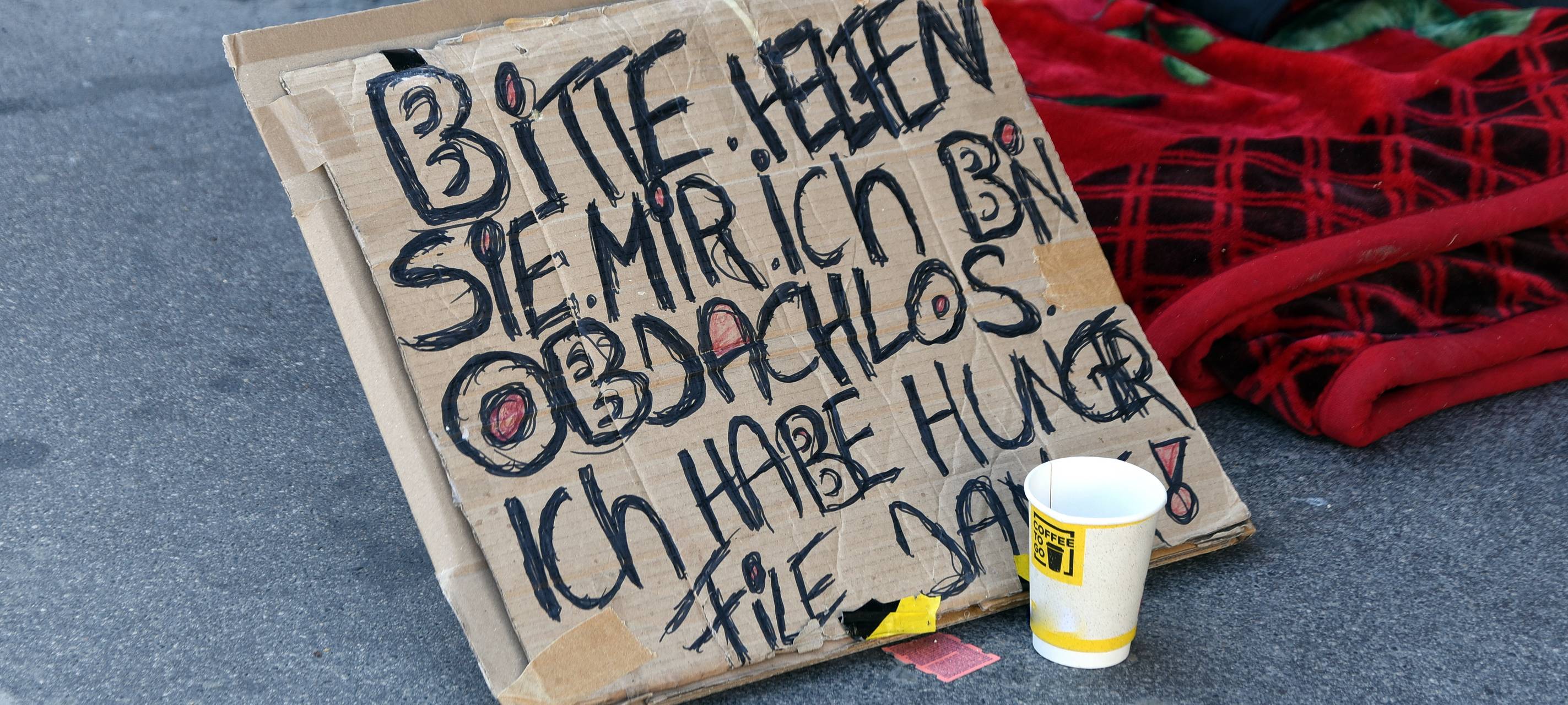 Ein selbst gemaltes Schild mit der Aufschrift: "Bitte helfen sie mir. Ich bin obdachlos. Ich habe Hunger. Danke."