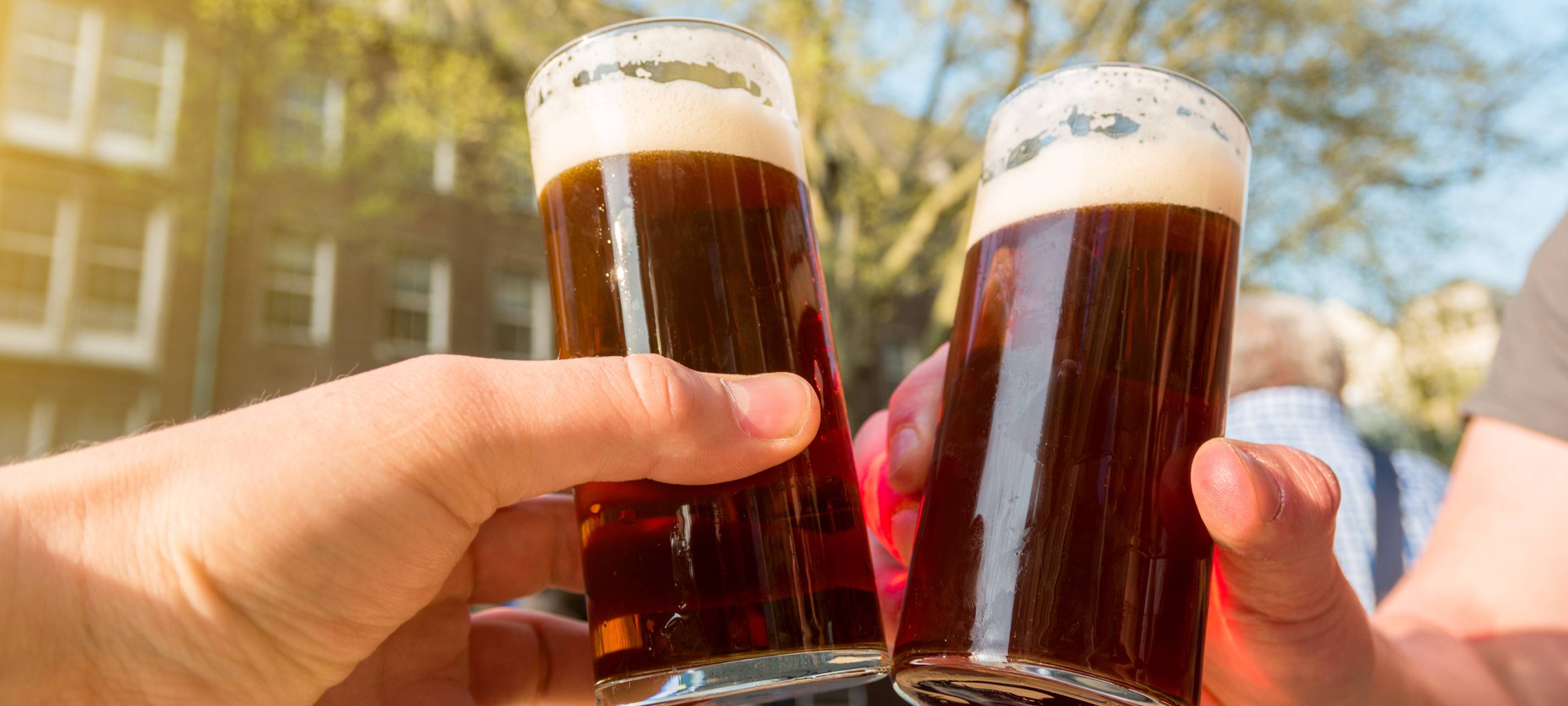 Zwei Personen stoßen mit zwei Altbiergläsern an.