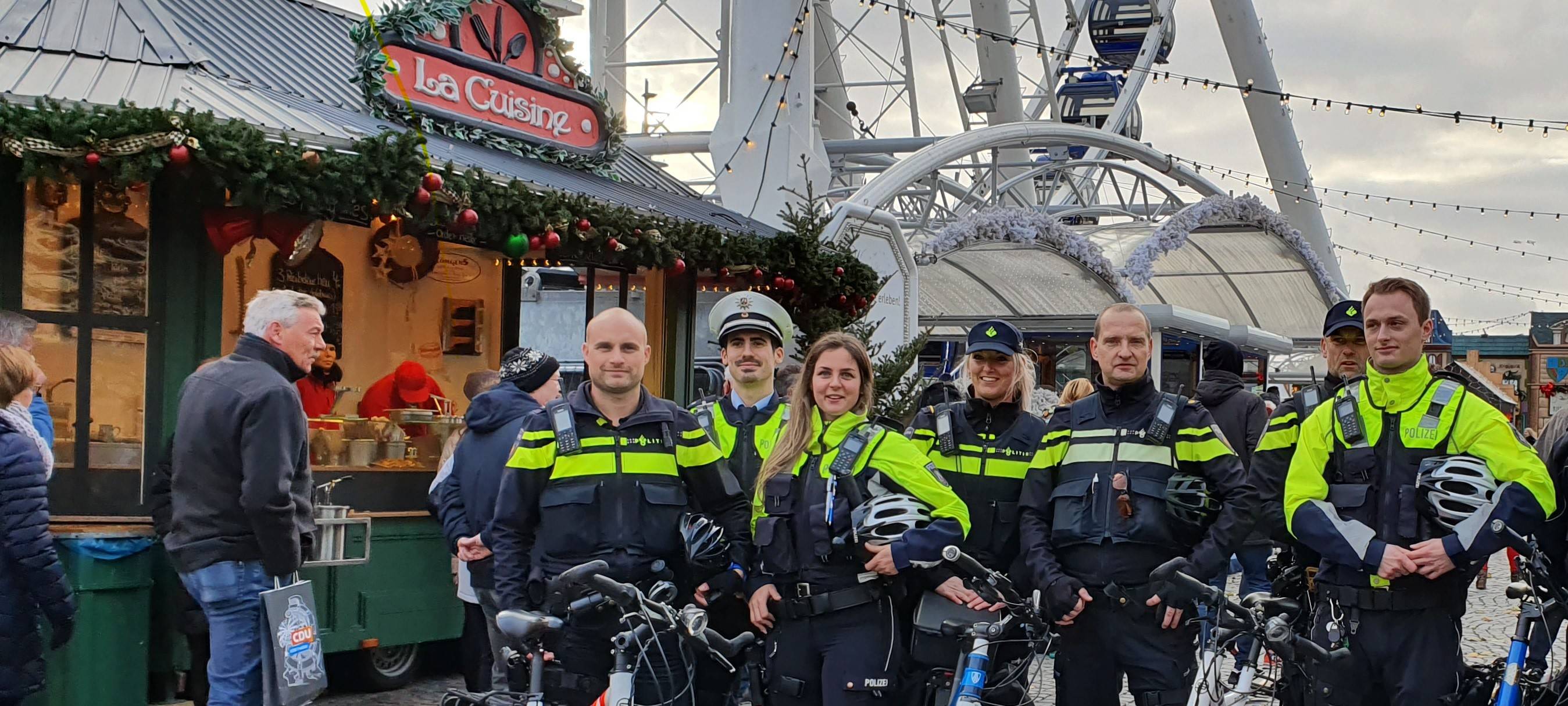 Weihnachtsmärkte im Blick: Polizisten und Düsseldorf und den Niederlanden auf Doppelstreife auf dem Burgplatz. Im Hintergrund dreht das Riesenrad seine Runden.