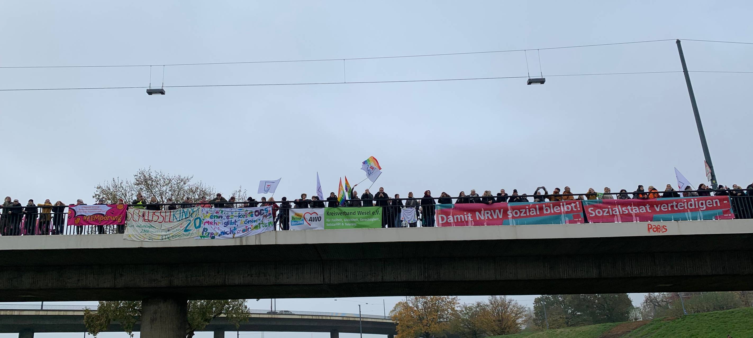 Großdemo auf den Rheinwiesen zum Thema "NRW bleib sozial". Viele Menschen stehen auf der Rheinkniebrücke und halten Plakate