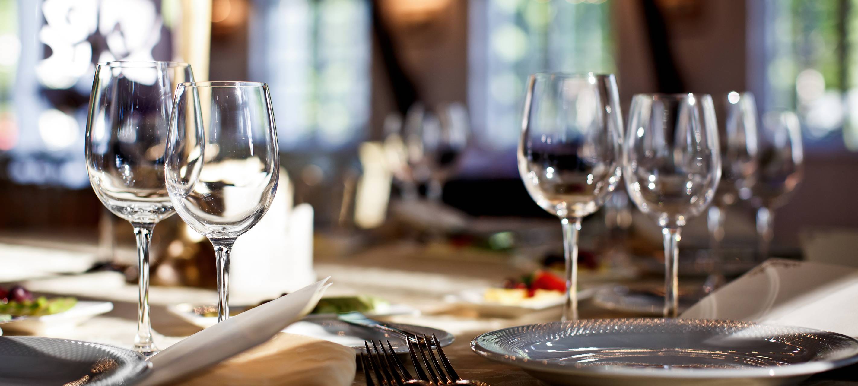 Ein gedeckter Tisch in einem Restaurant. Mit Glästern, Tellern und Besteck.