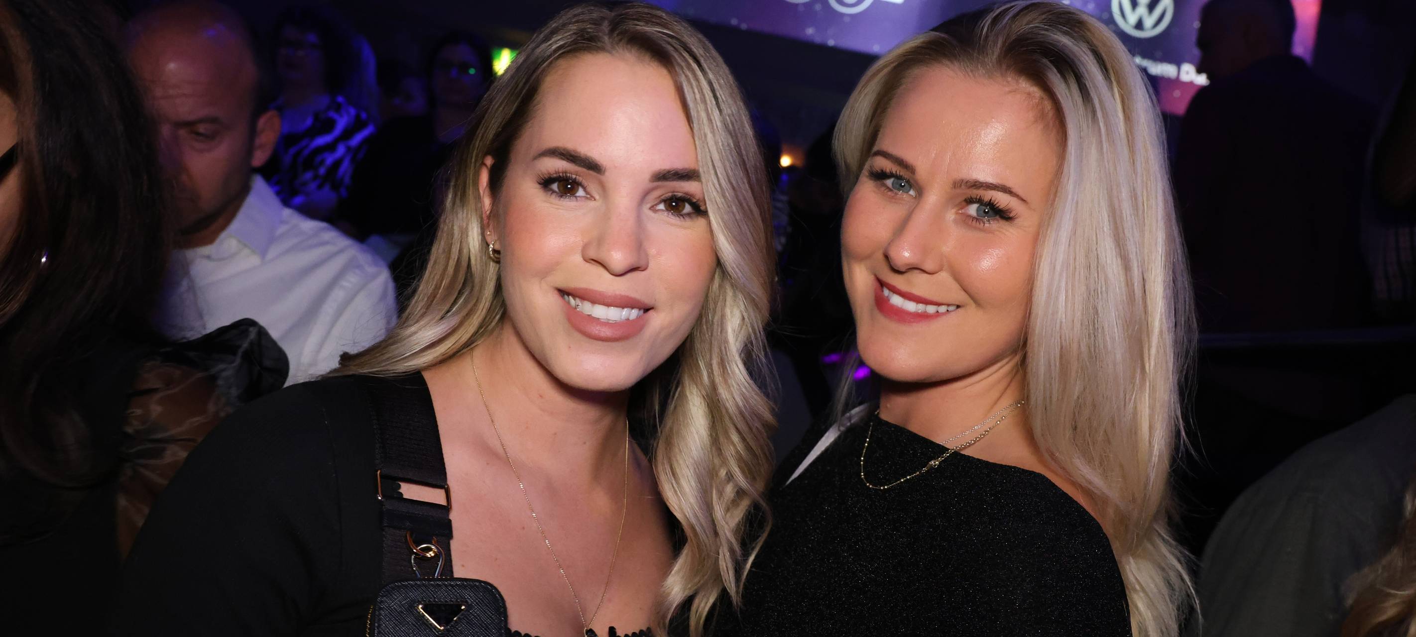 Zwei Damen mit blonden langen Haaren posieren für ein gemeinsames Foto in der Nachtresidenz, sie lächeln. Im Hintergrund ist das Logo vom Hauptsponsor Gottfried Schultz zu sehen,