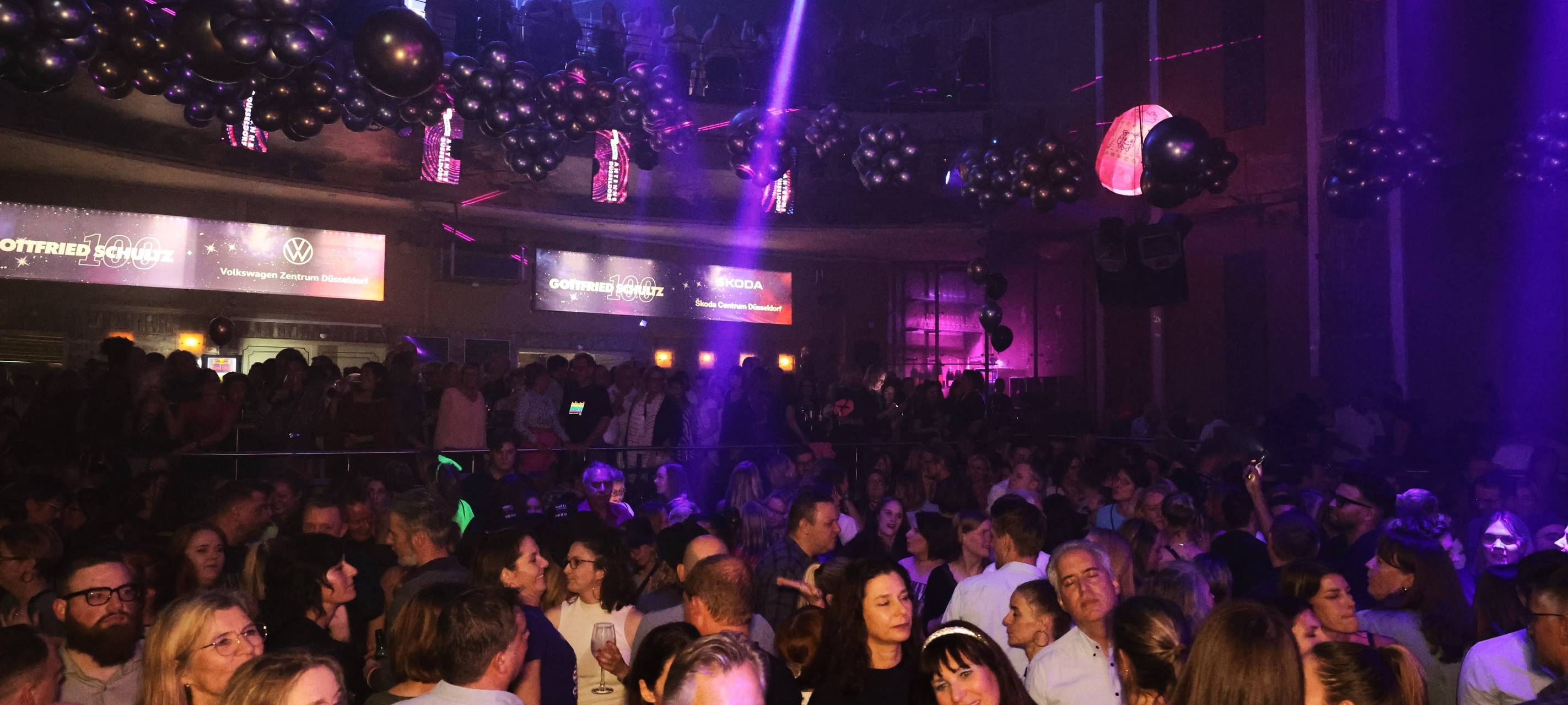 Eine feiernde Menschenmenge in der Nachtresidenz. Viele Lichtquellen an der Decke kreieren eine Party-Atmosphäre.