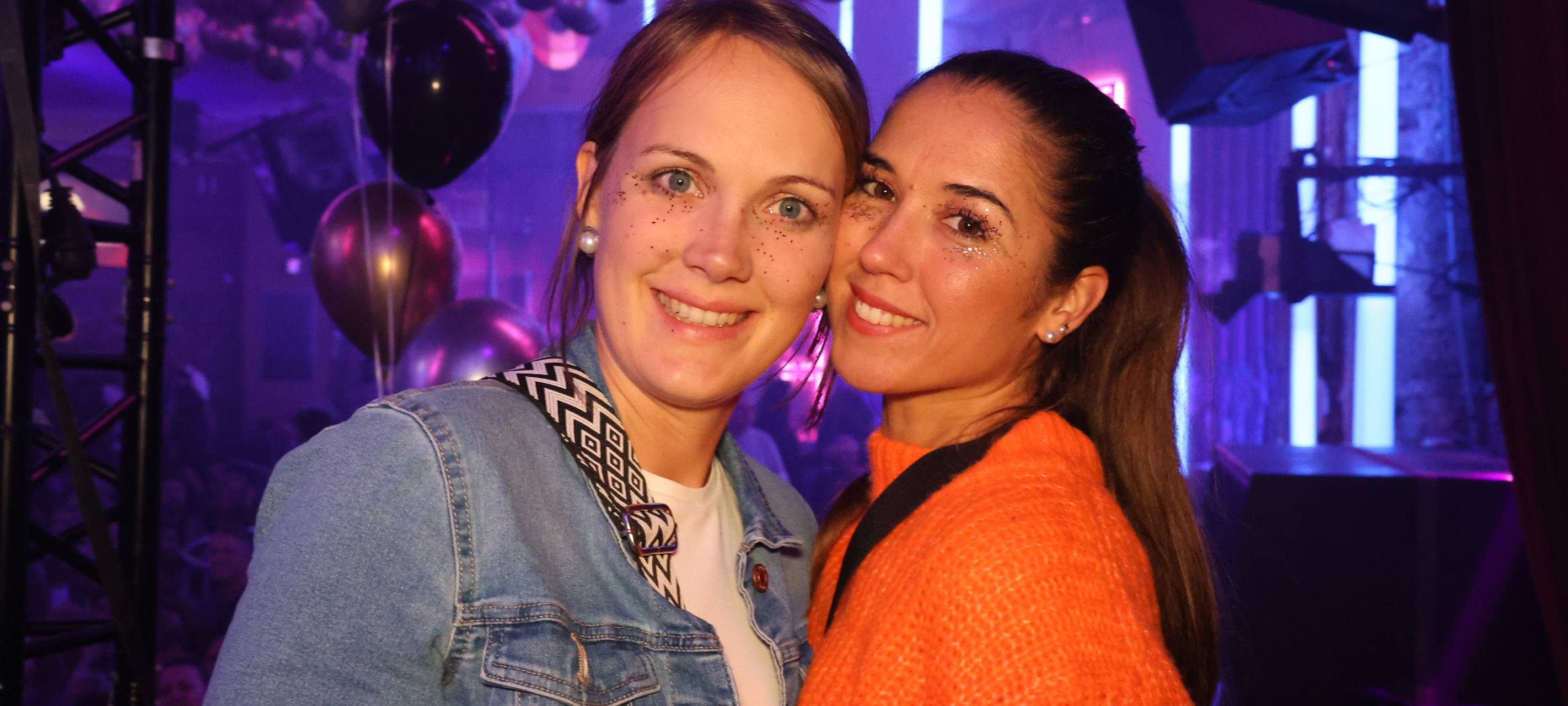 Zwei Damen posieren für ein Foto in der Nachtresidenz. Sie sind beide mit Glitzer im Gesicht geschminkt.