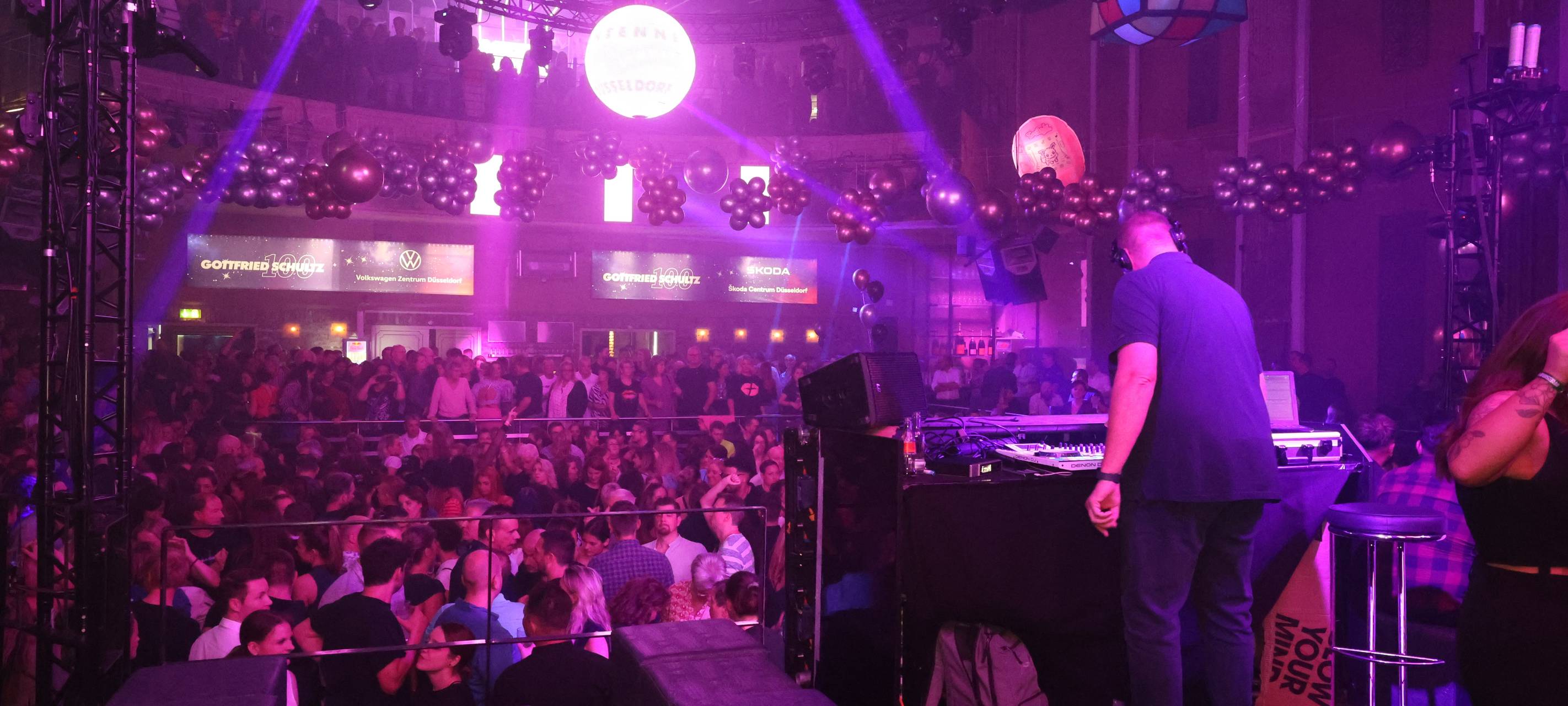 Antenne Düsseldorf-DJ Marc Pesch steht am Mischpult und legt Musik auf. Er steht mit dem Rücken zur Kamera. Im Hintergrund sieht man die feiernde Menge.