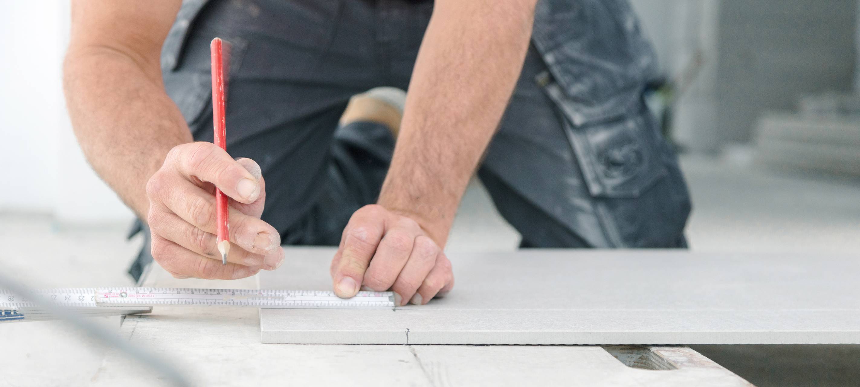 Ein Handwerker nimmt auf einer Arbeitsfläche mit einem Zollstock Maß.