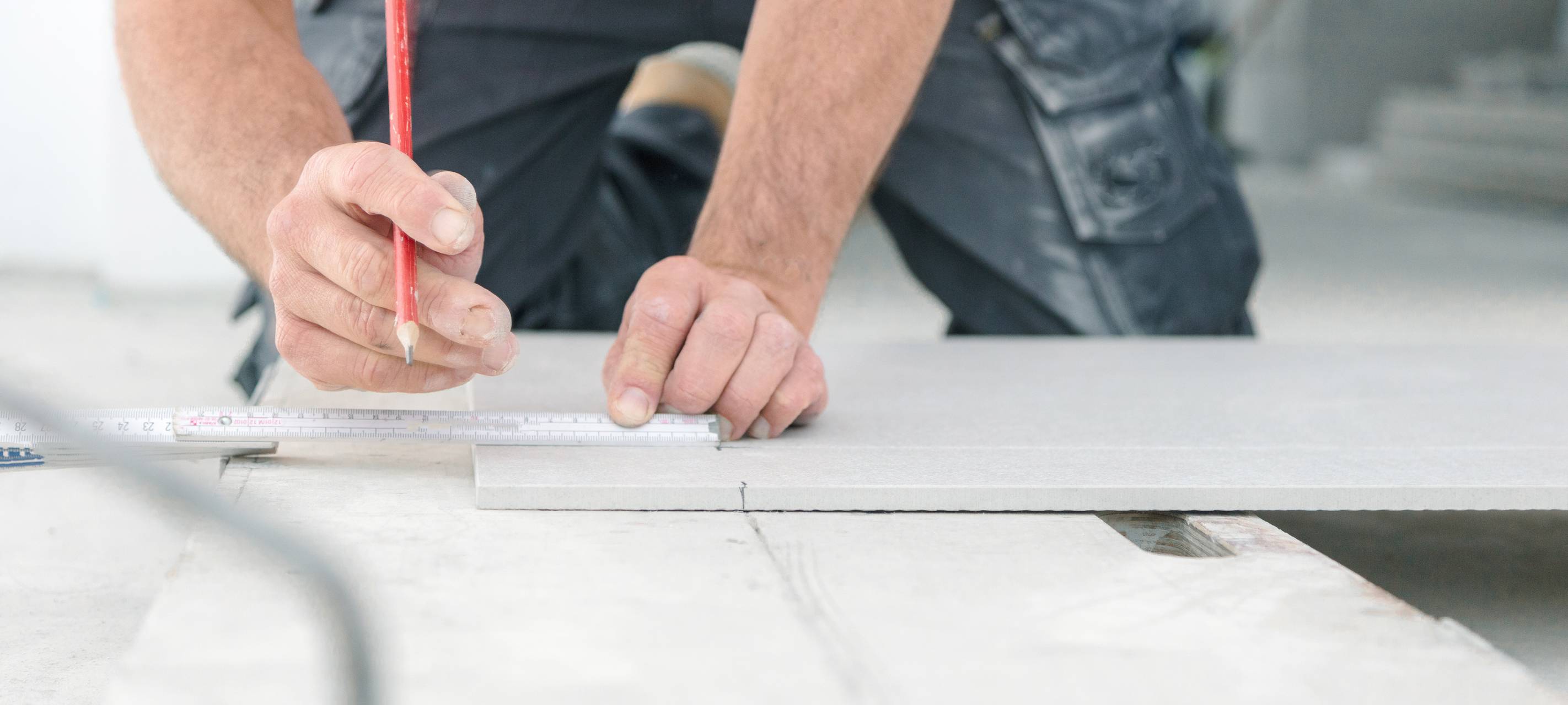 Ein Handwerker nimmt auf einer Arbeitsfläche mit einem Zollstock Maß.