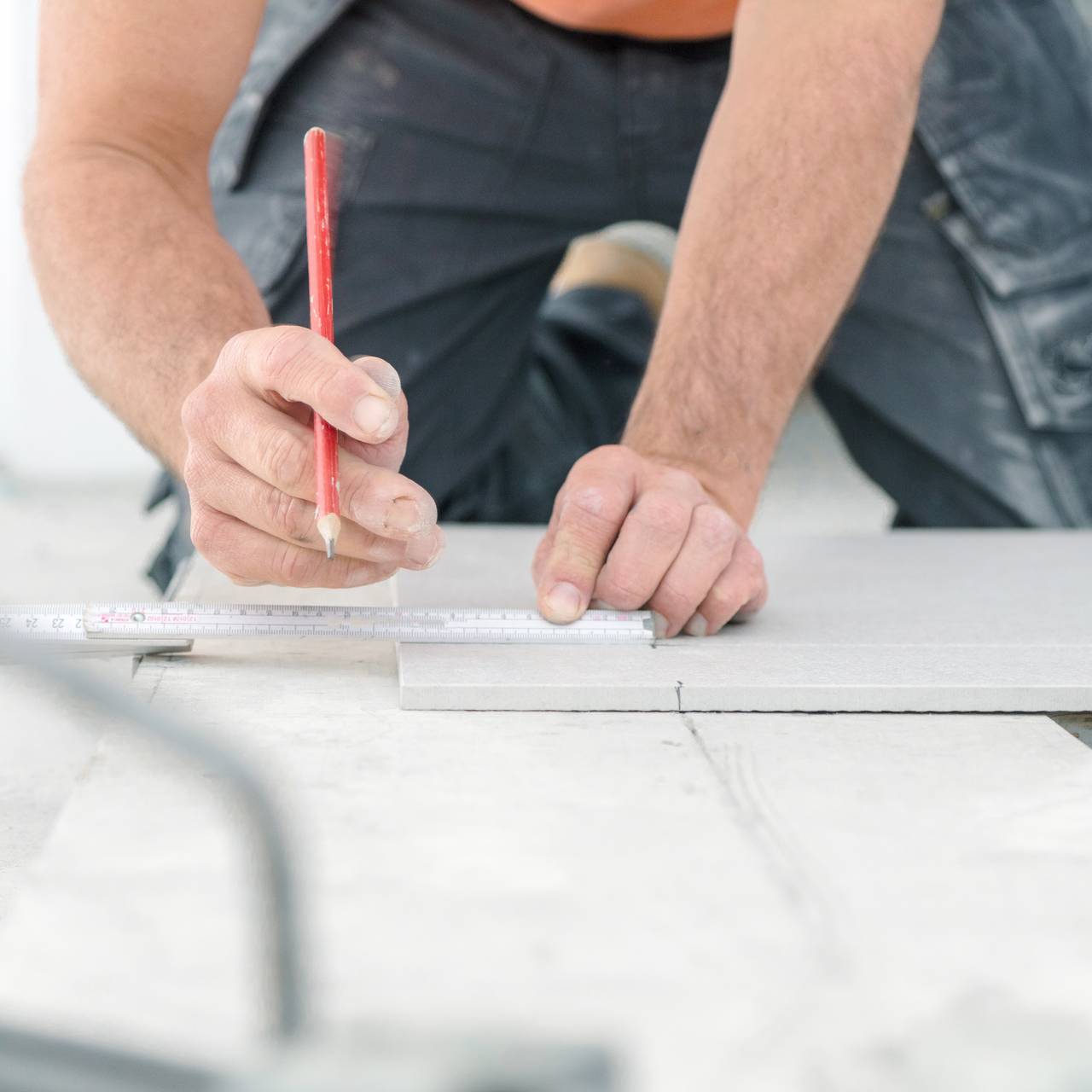 Ein Handwerker nimmt auf einer Arbeitsfläche mit einem Zollstock Maß.