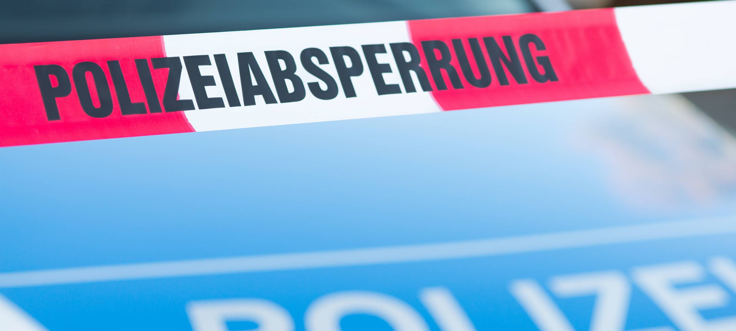 Absperrband vor einem Polizeiauto.
