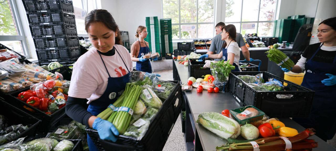 Freiwillige Helfer und Helferinnen sortieren und geben Lebensmittel bei der Tafel an Bedürftige aus.