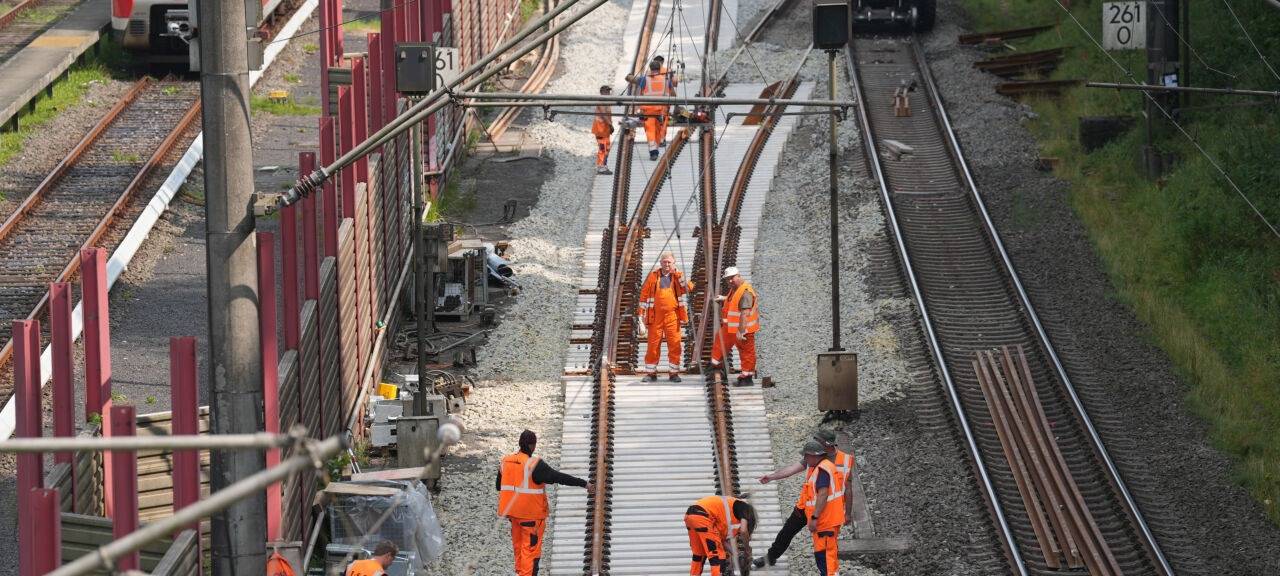 Bauarbeiter führen Sanierungsmaßnahmen an einer Gleisstrecke durch.