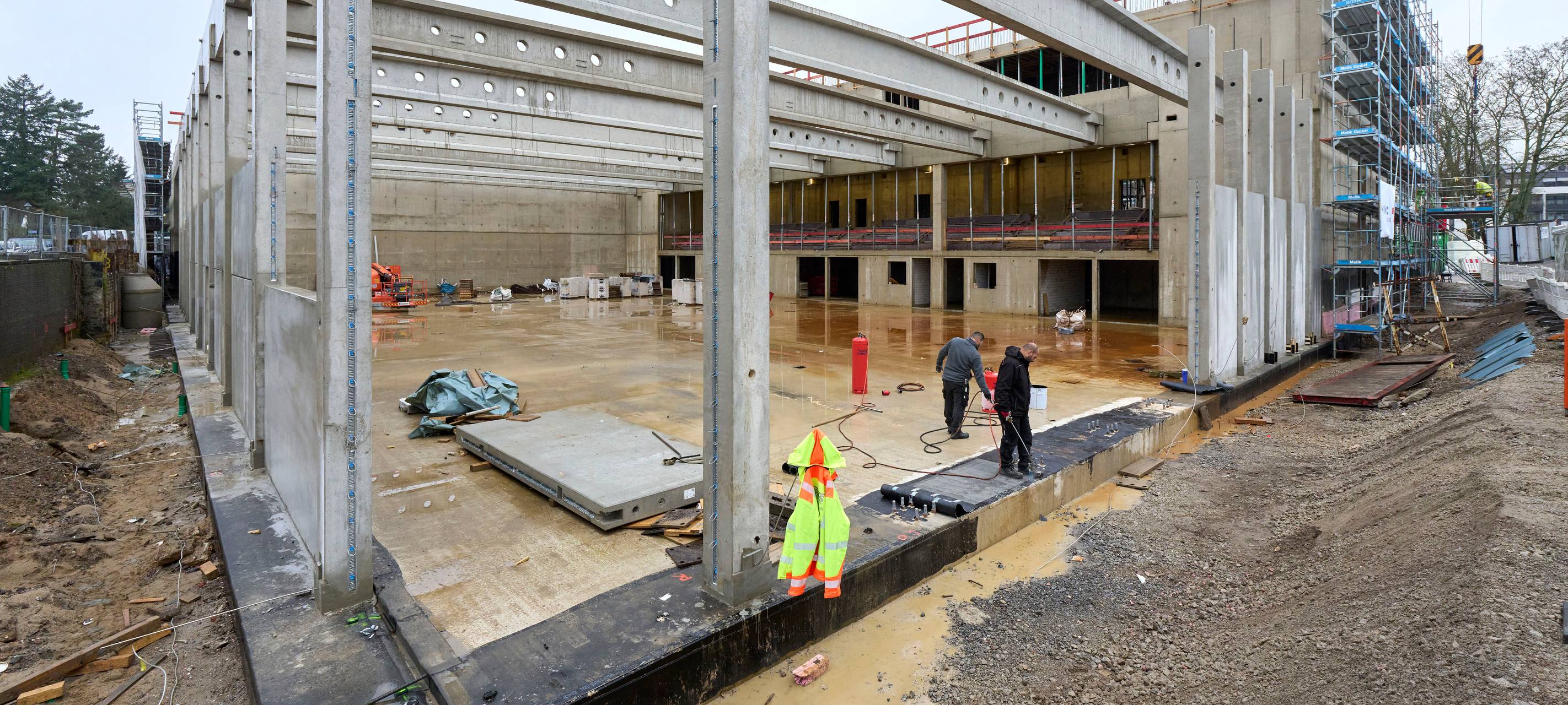 Bild von der Bauphase des Gymansiums in Gerresheim. Zu sehen sind Bauarbeiter, ein Kran und Gerüste.