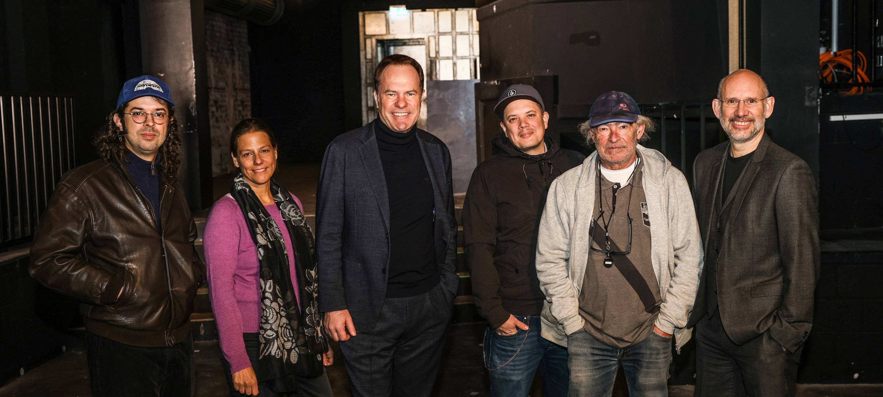OB Keller und die neue Crew für den Ratinger Hof in der abgedunkelten Location. Von links nach rechts stehen nebeneinander: Felix Wursthorn, Music Düsseldorf; Daniela Stork, D.LIVE; OB Keller; Nico Hamm, concert team nrw; Berni Lewkowicz, concert team nrw und Michael Brill, CEO D.LIVE.