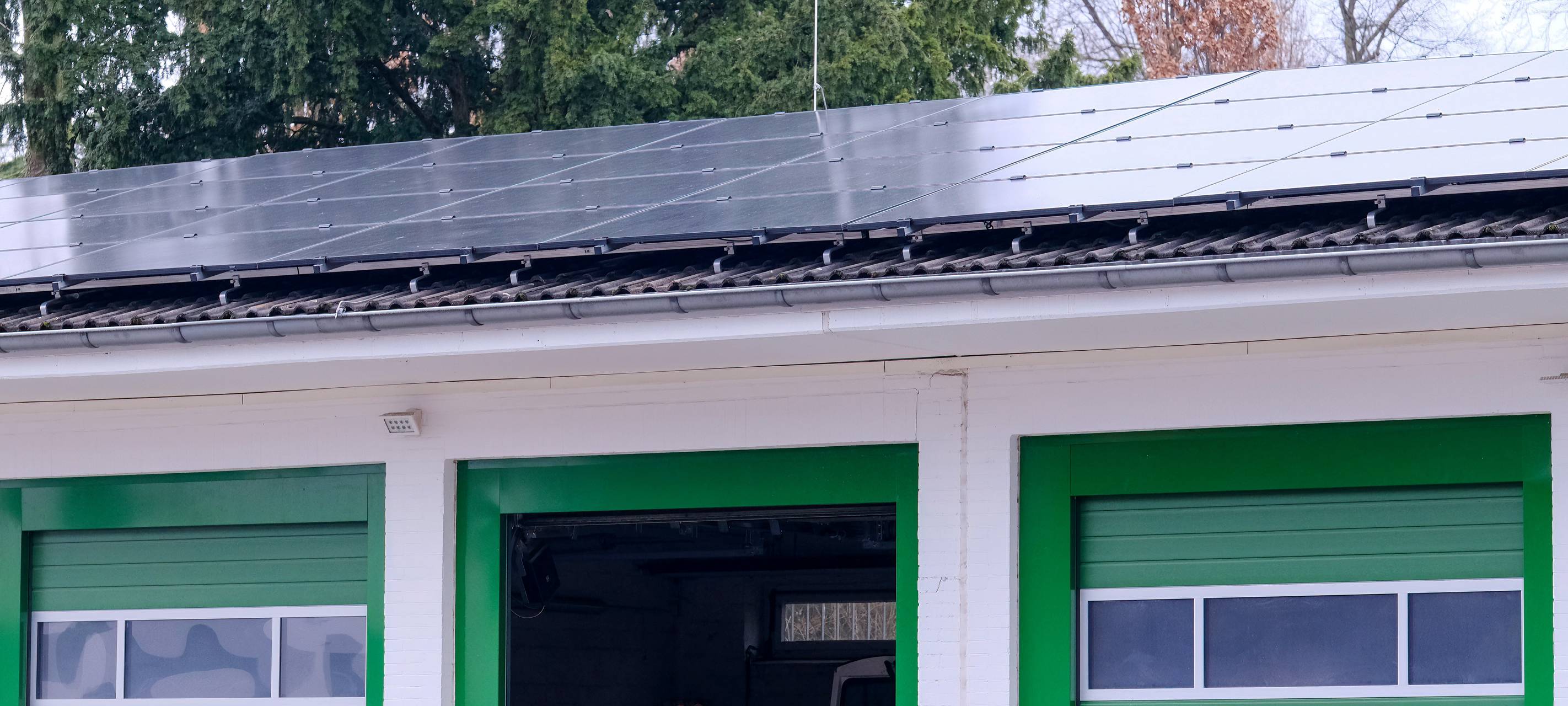 Eine neue Photovoltaikanlage befindet sich auf dem Dach des Betriebshofes am Friedhof Stoffeln. Das Haus ist in weiß und vor allem grün gehalten. Im Hintergrund sind Bäume zu sehen.