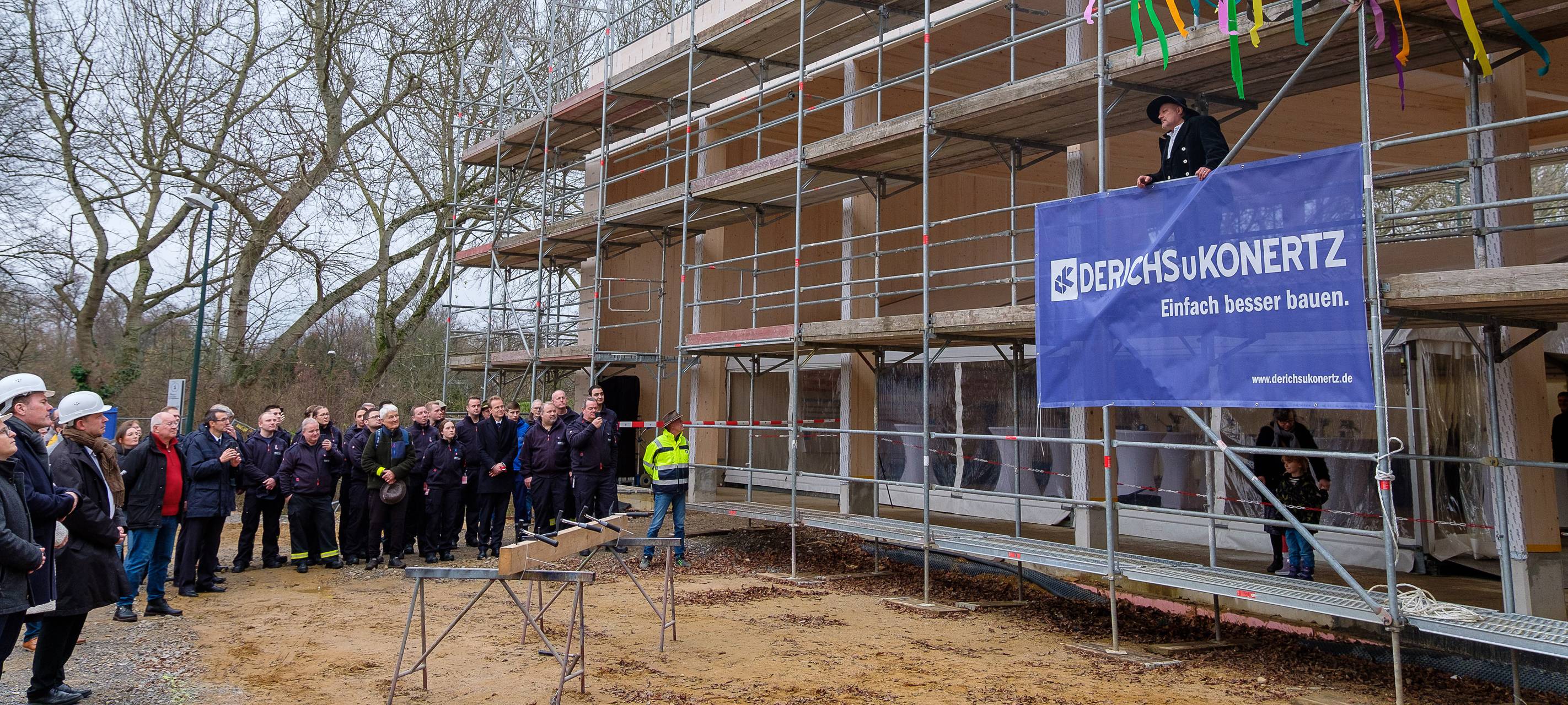 An der Baustelle der neuen Feuerwache in Kaiserswerth wird Richtfest gefeiert. Ein Bauarbeiter spricht zu den anwesenden Gästen.