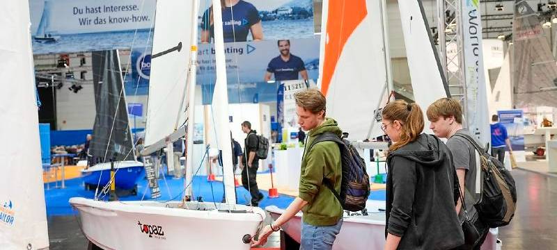 Besucherinnen und Besucher laufen über die Messe boot und schauen sich ein Boot an.
