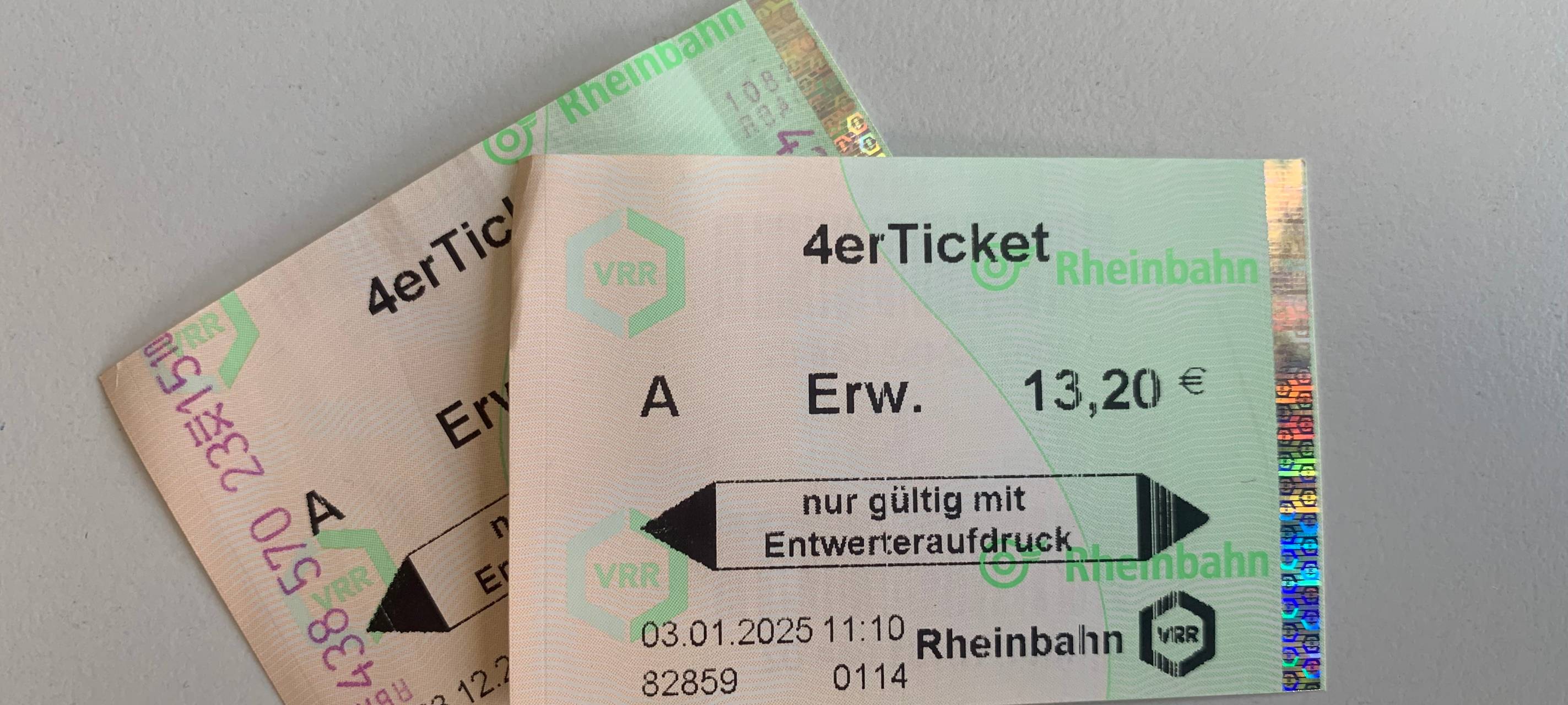 Zwei Papiertickets der Rheinbahn liegen auf einem weißen Tisch.