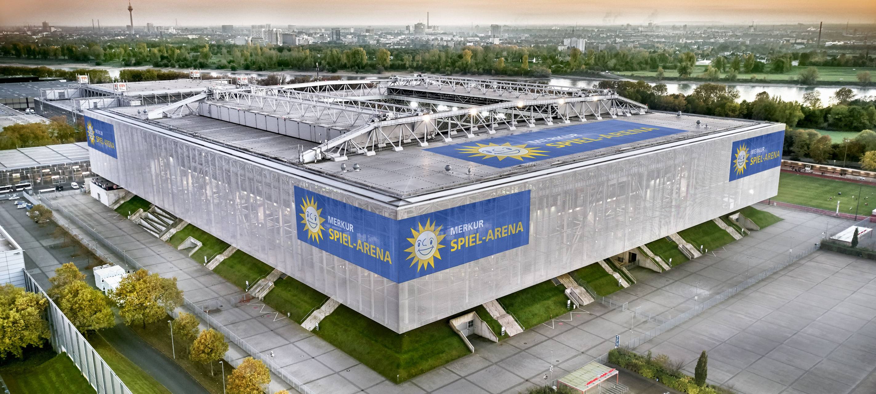 Die Merkur-Spiel-Arena im Vordergrund vor der Düsseldorfer Kulisse. Im Hintergrund sind unter anderem der Rhein und der Fernsehturm zu sehen.
