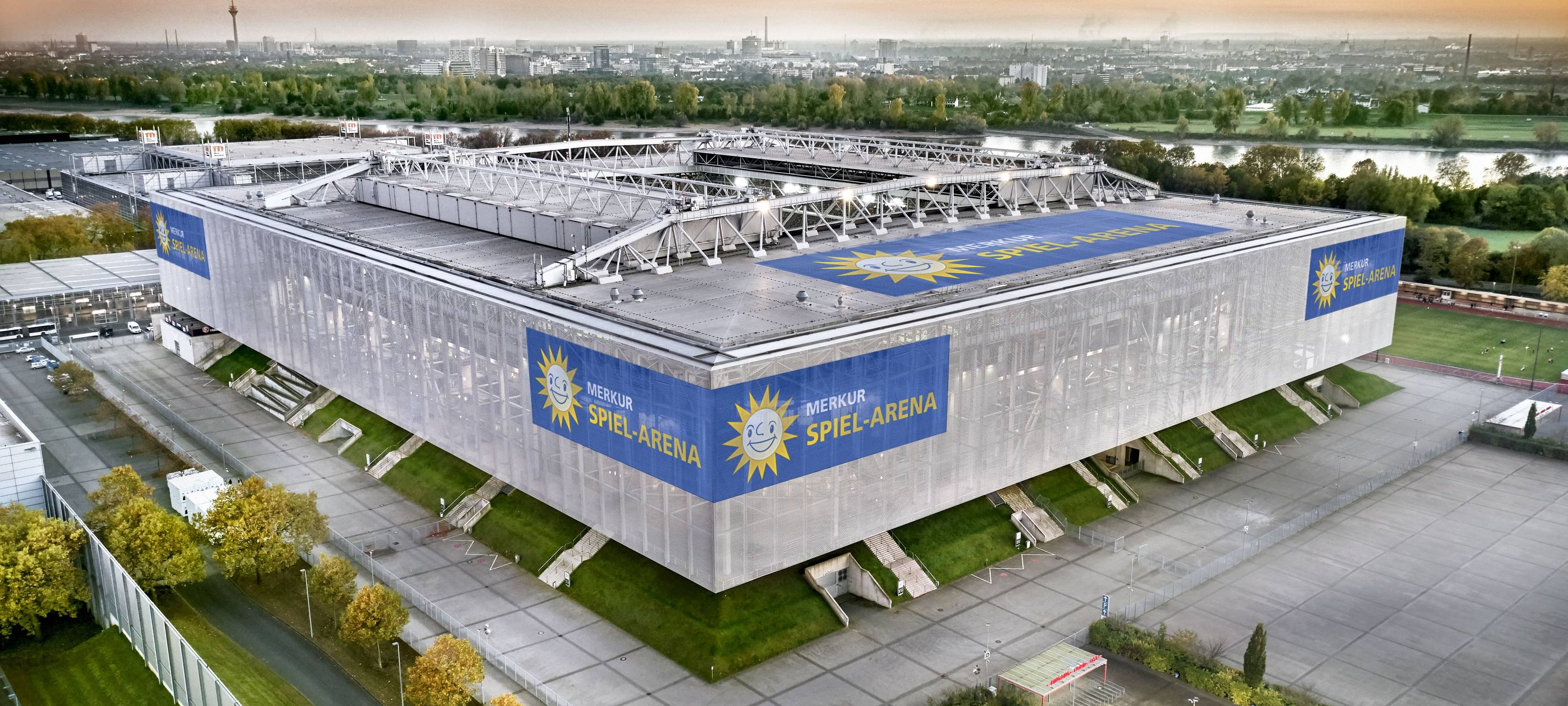 Die Merkur-Spiel-Arena im Vordergrund vor der Düsseldorfer Kulisse. Im Hintergrund sind unter anderem der Rhein und der Fernsehturm zu sehen.