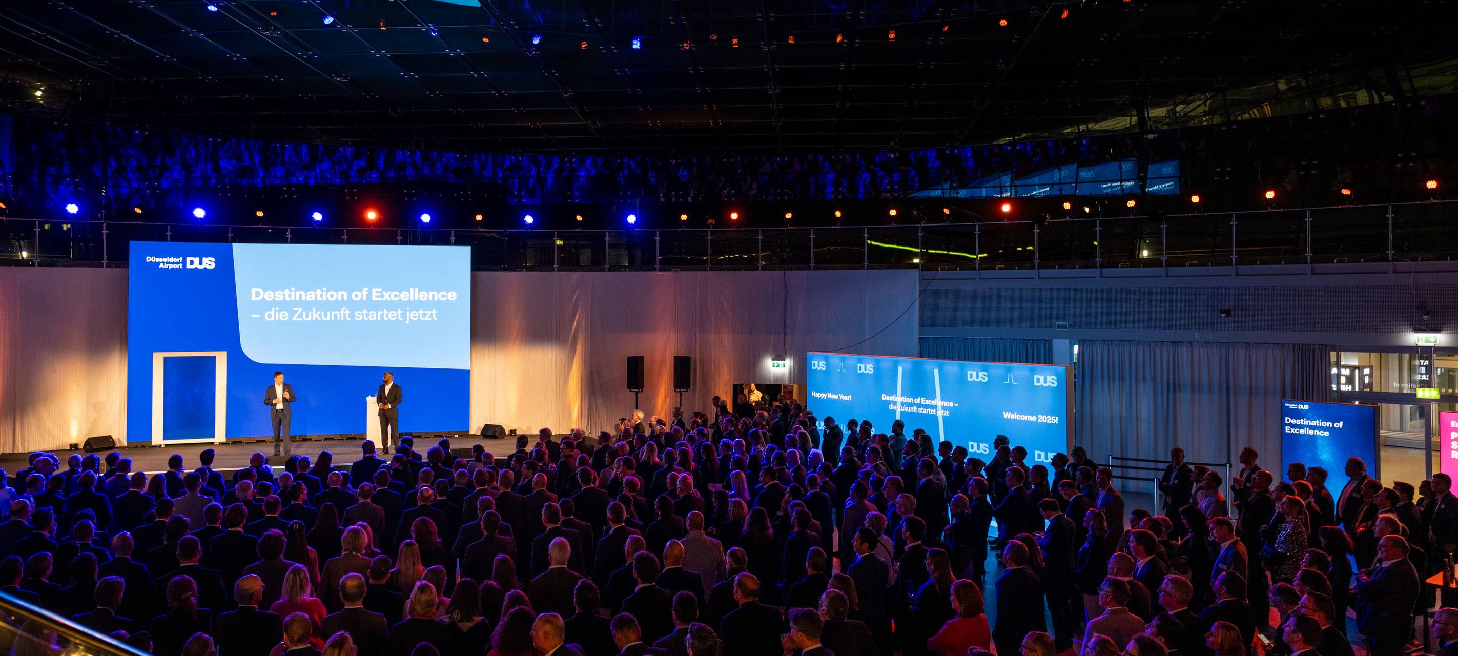 Rund 800 Gäste beim Neujahrsempfang des Flughafen Düsseldorf 2025. Auf der Bühne stehen die Geschäftsführer des Flughafens und halten einen Vortrag