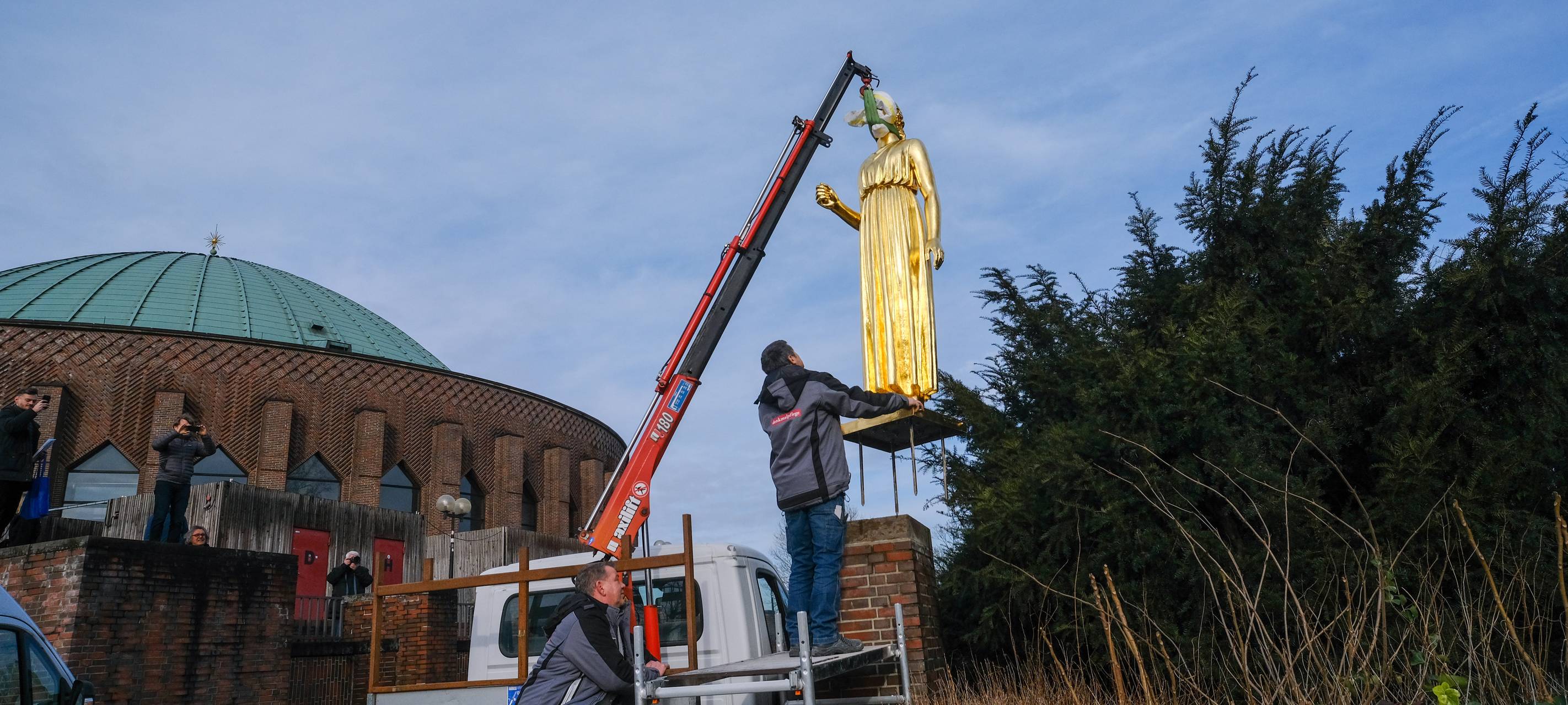 Die sanierte, goldene Statue "Pallas Athene" wird mit einem Kran wieder in der Nähe der Tonhalle aufgestellt. Die Figur hängt hier noch in der Luft.