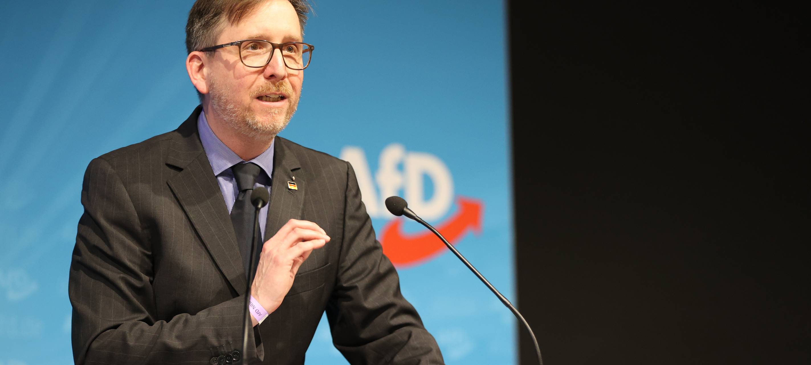 Marco Vogt von der AfD steht auf einer Bühne vor einem Mikrofon und hält eine Rede.