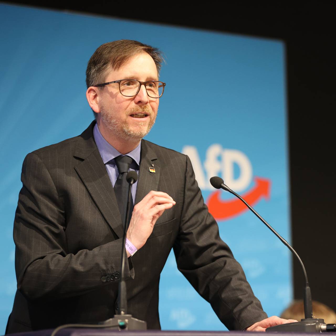Marco Vogt von der AfD steht auf einer Bühne vor einem Mikrofon und hält eine Rede.