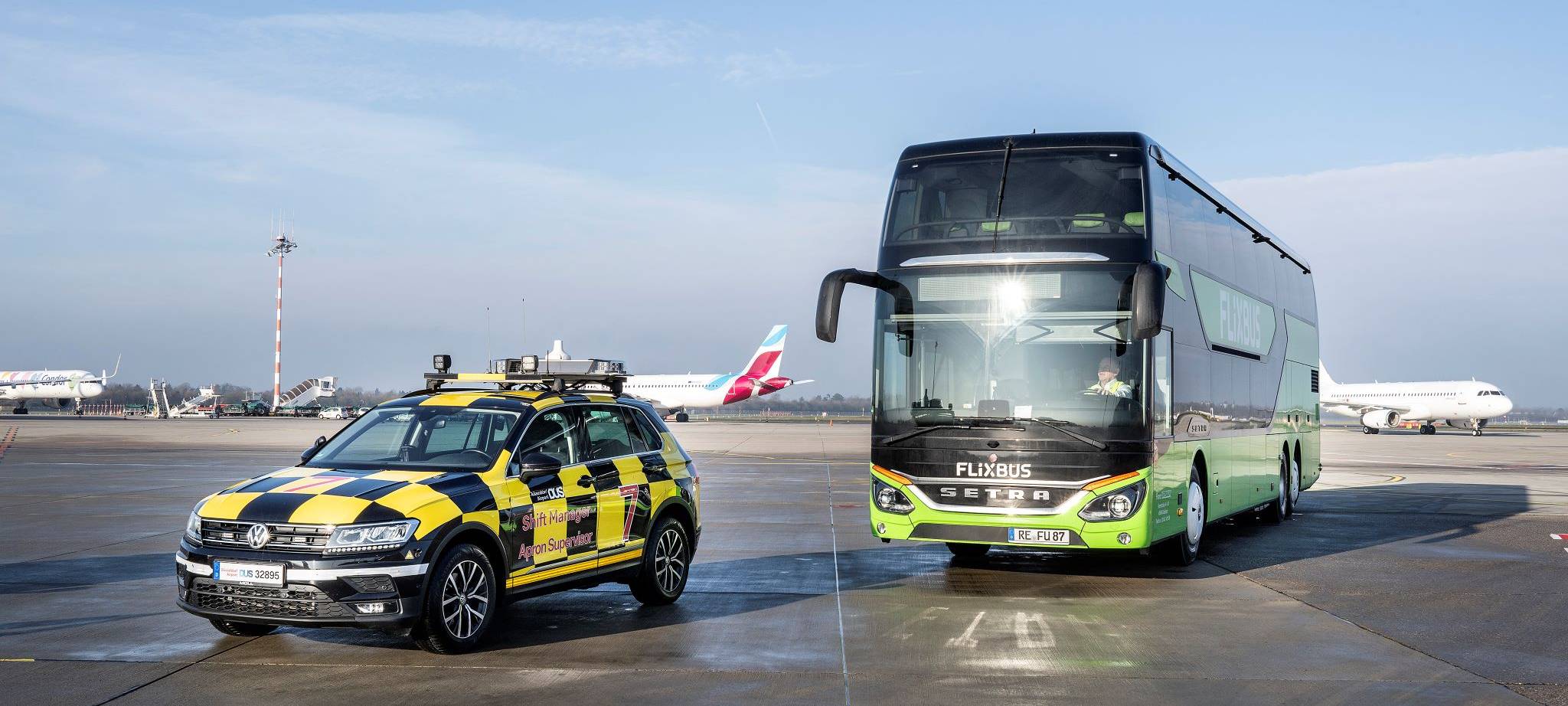 Ein FlixBus am Düsseldorfer Flughafen hiner einem Follow Me-Fahrzeug