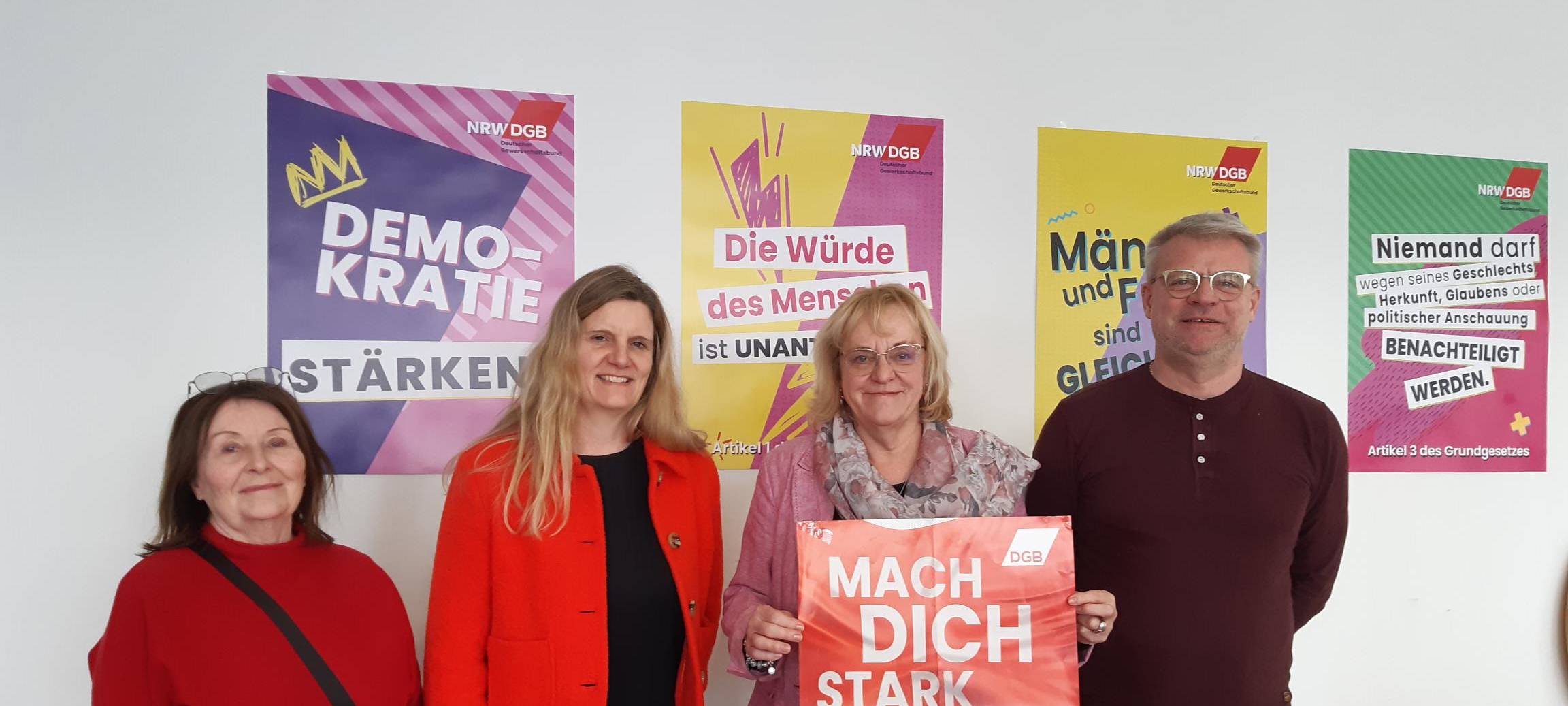 Sylvia Burkert, Dinah Trompeter, Sigrid Wolf und Dirk Jehle stehen vor Demo-Plakaten der DGB.