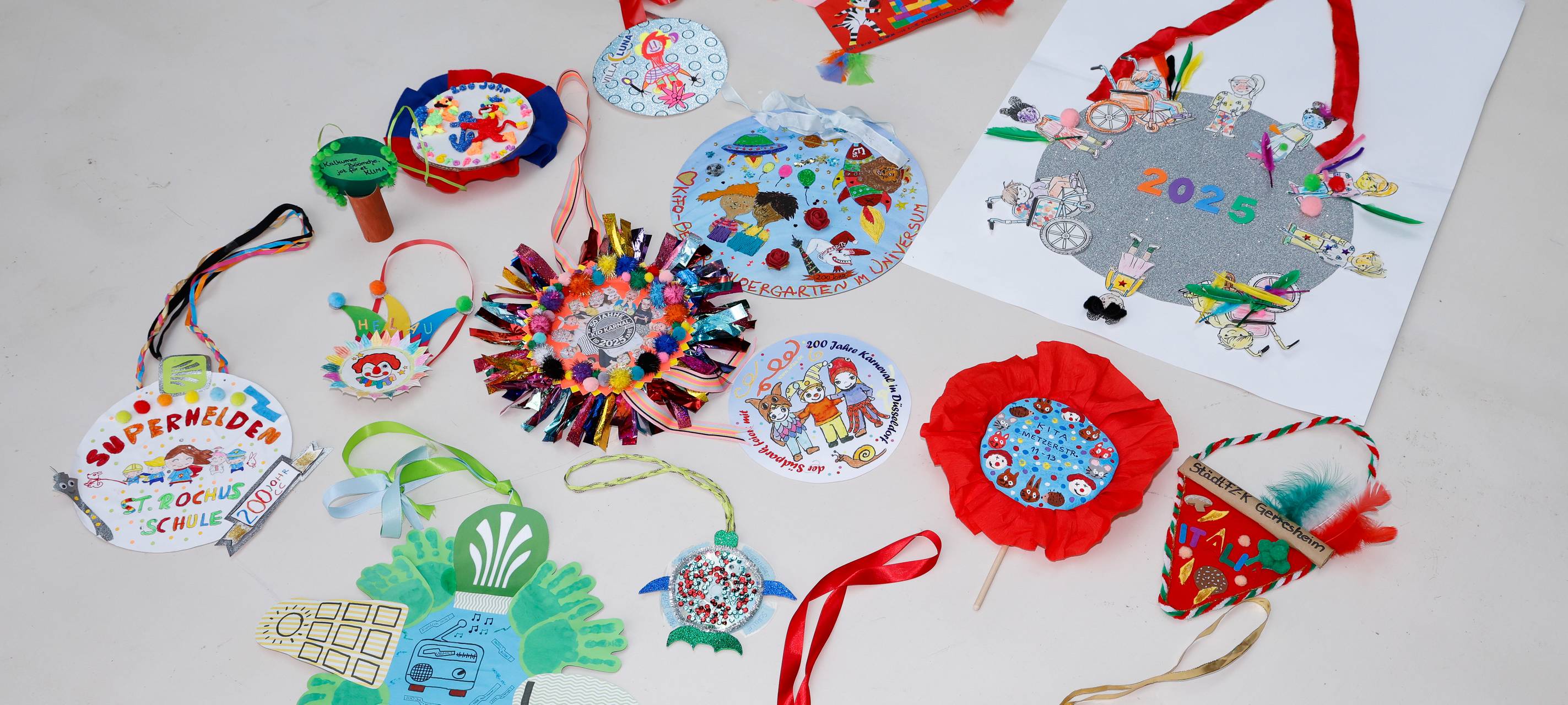 Viele bunt-gestaltete Orden aus Papier und Pappe, erstellt von diversen Kita-Gruppen und Schulklassen