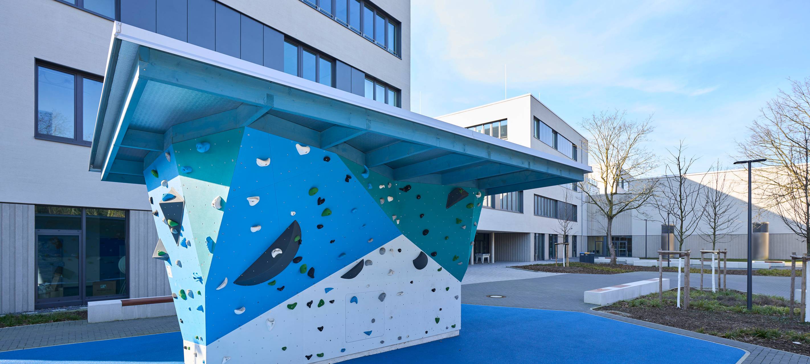 Schulhof vor den neuen Schulgebäuden an der Aldekerkstraße in Heerdt. Dort gibt es auch Bänke, Spiel-, Sport- und Klettergeräte.