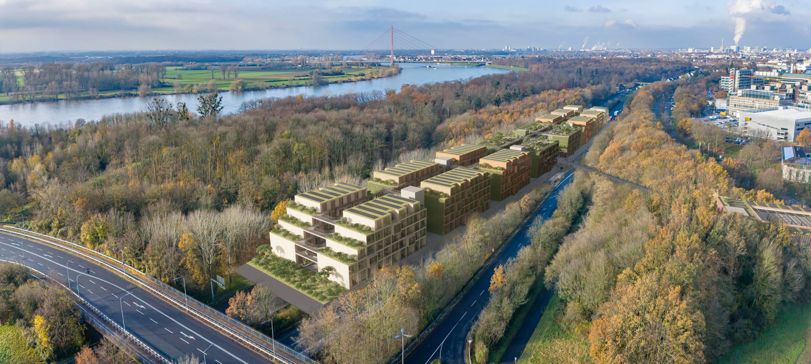 Bild der Münchener Straße mit der geplanten Wohnbebauung oberhalb der Straße. Im Hintergrund sind viele Bäume und der Rhein zu sehen.