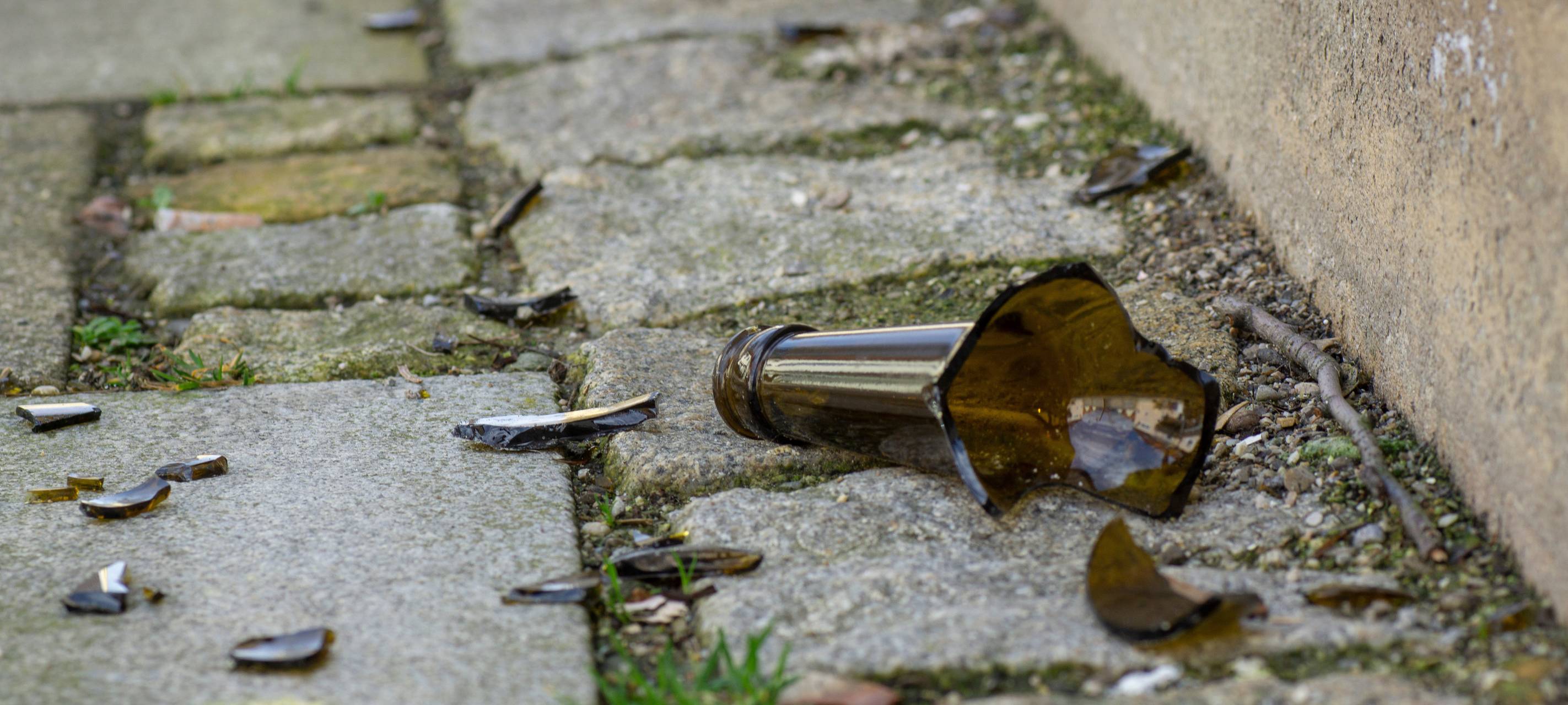 Eine zerbrochene Bierflasche liegt auf der Straße.