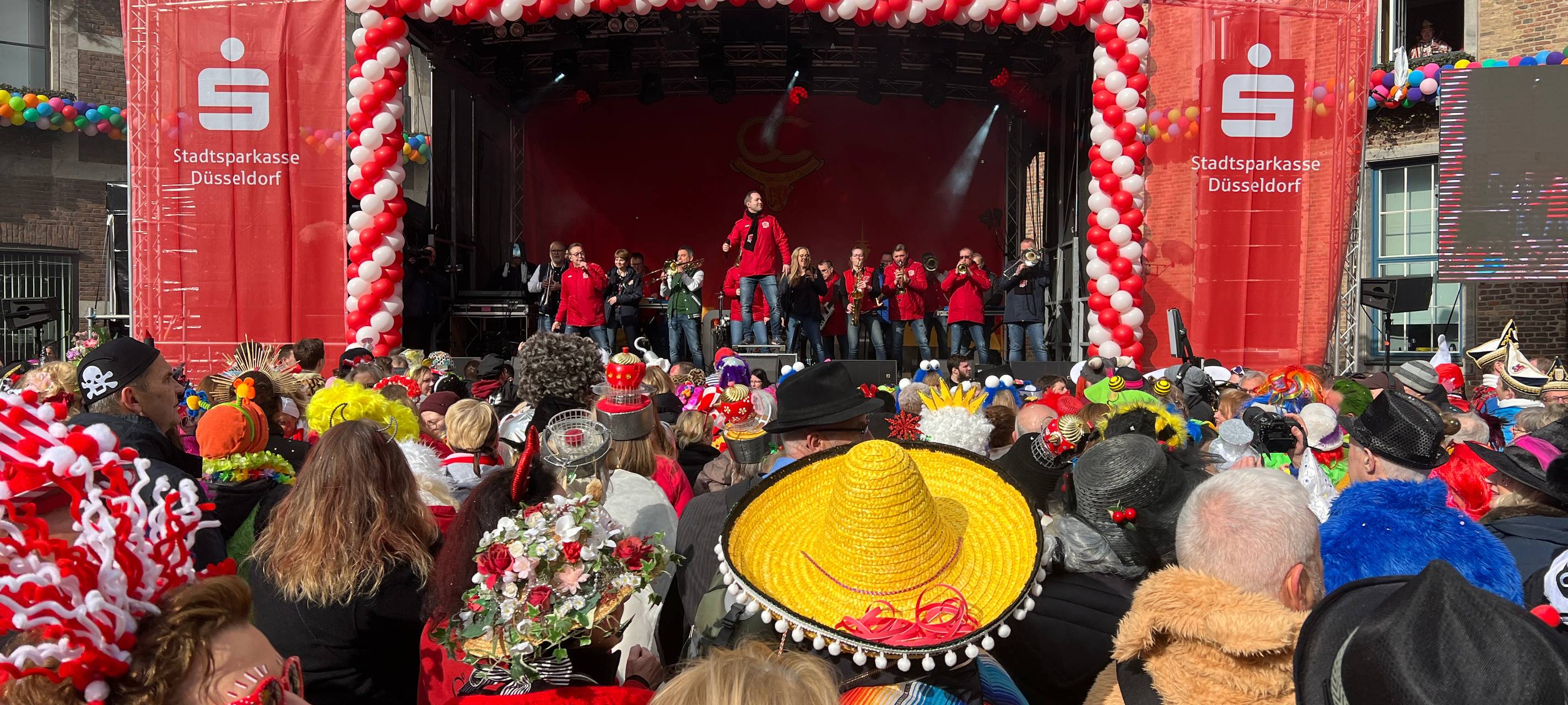 Viele verkleidete Jecken feiern zusammen mit den Swinging Funfares an Altweiber auf dem Rathausplatz
