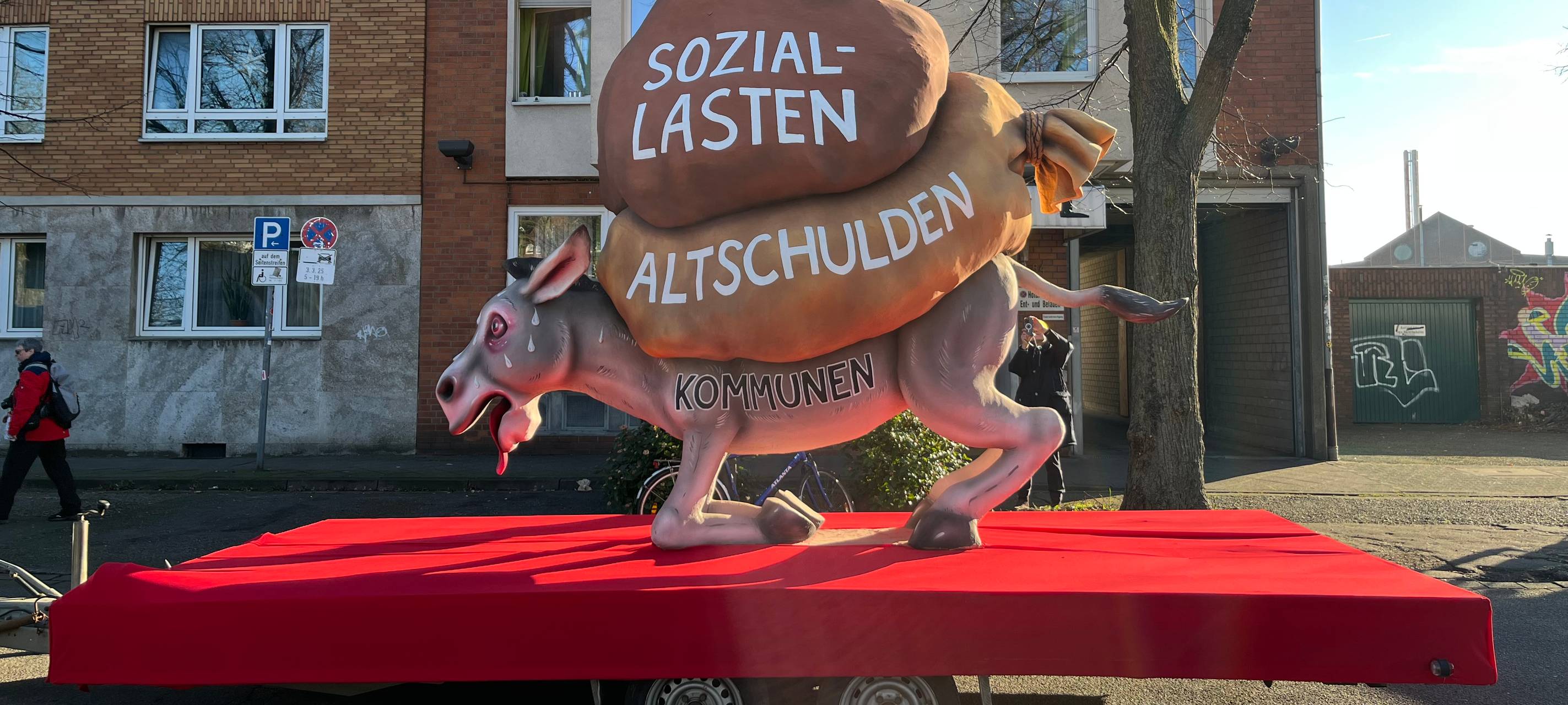 Mottowagen beim Karneval: Die Kommunen als Esel werden von Altschulden und Soziallasten erdrückt.