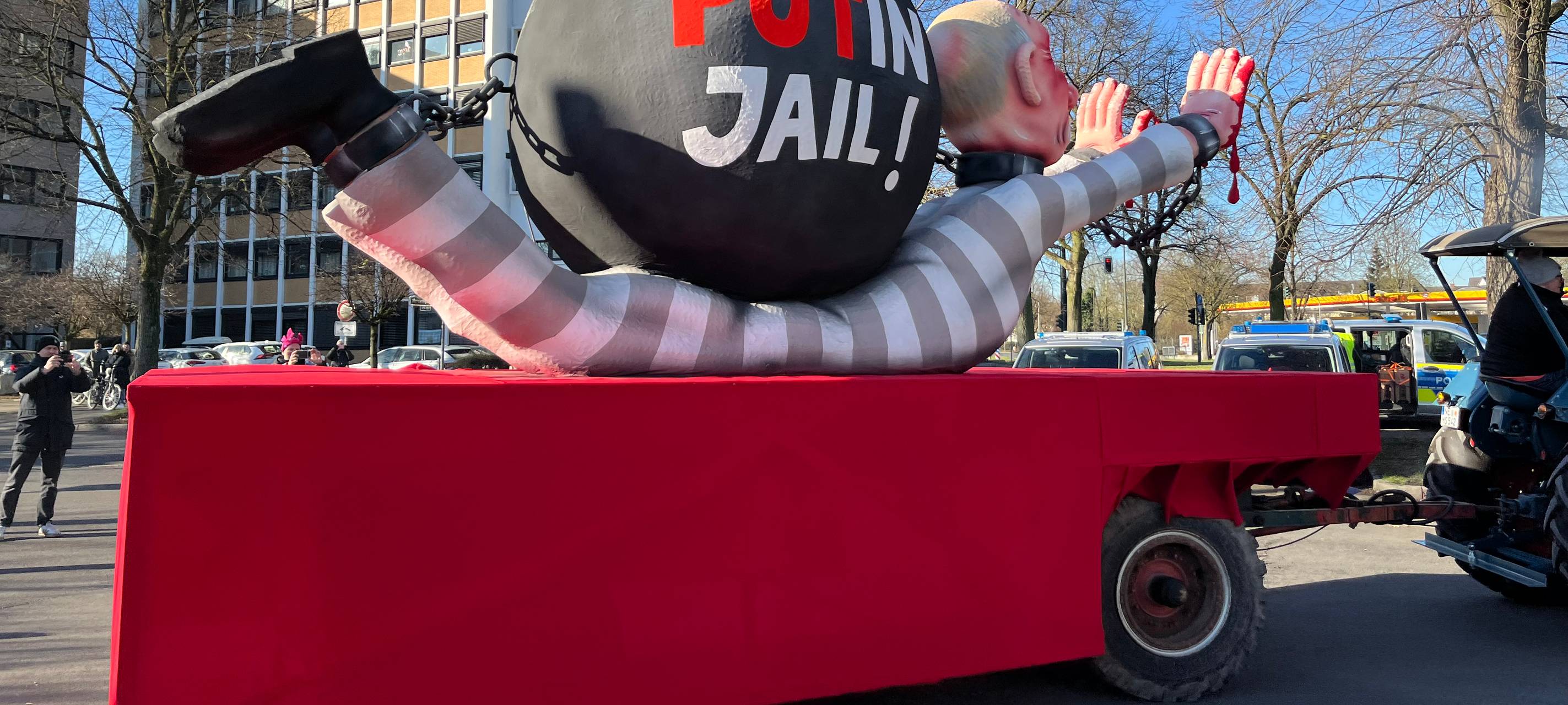 Mottowagen beim Karneval: Putin als Häftling angezogen liegt am Boden, auf ihm eine Sträflingskugel.
