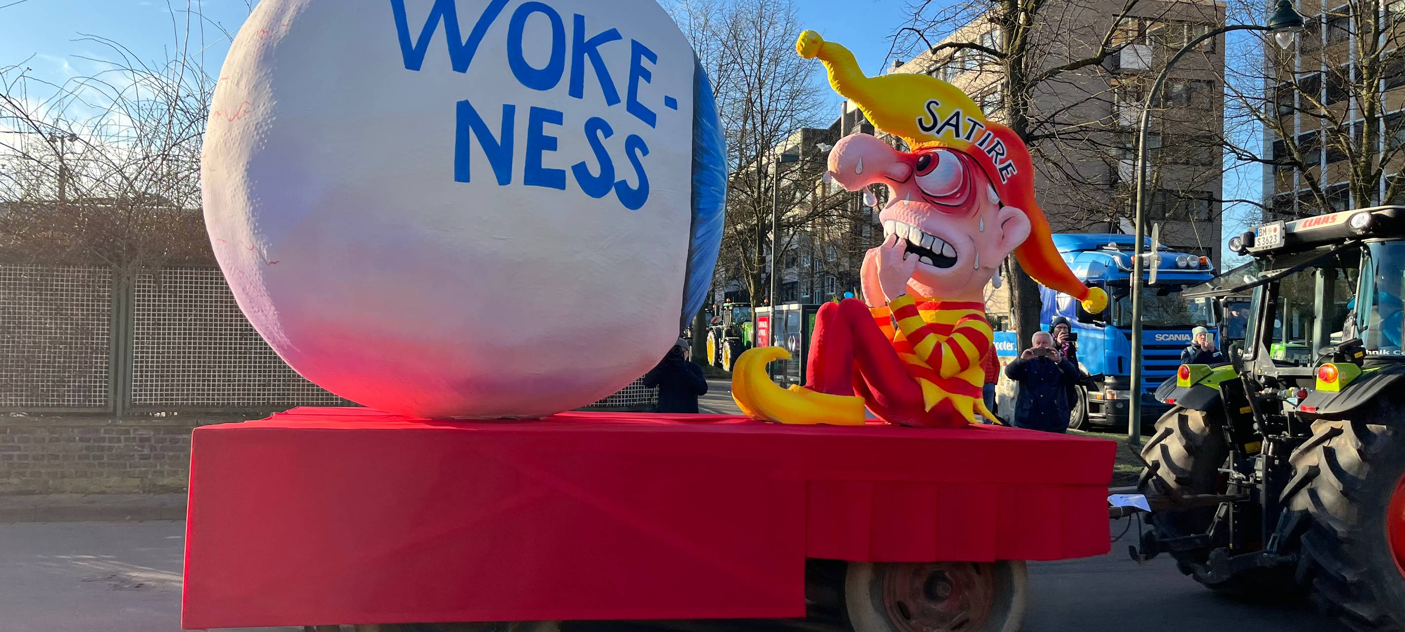Mottowagen beim Karneval: Ein riesiges Auge, auf dem Wokeness steht, schaut auf die zitternde Satire