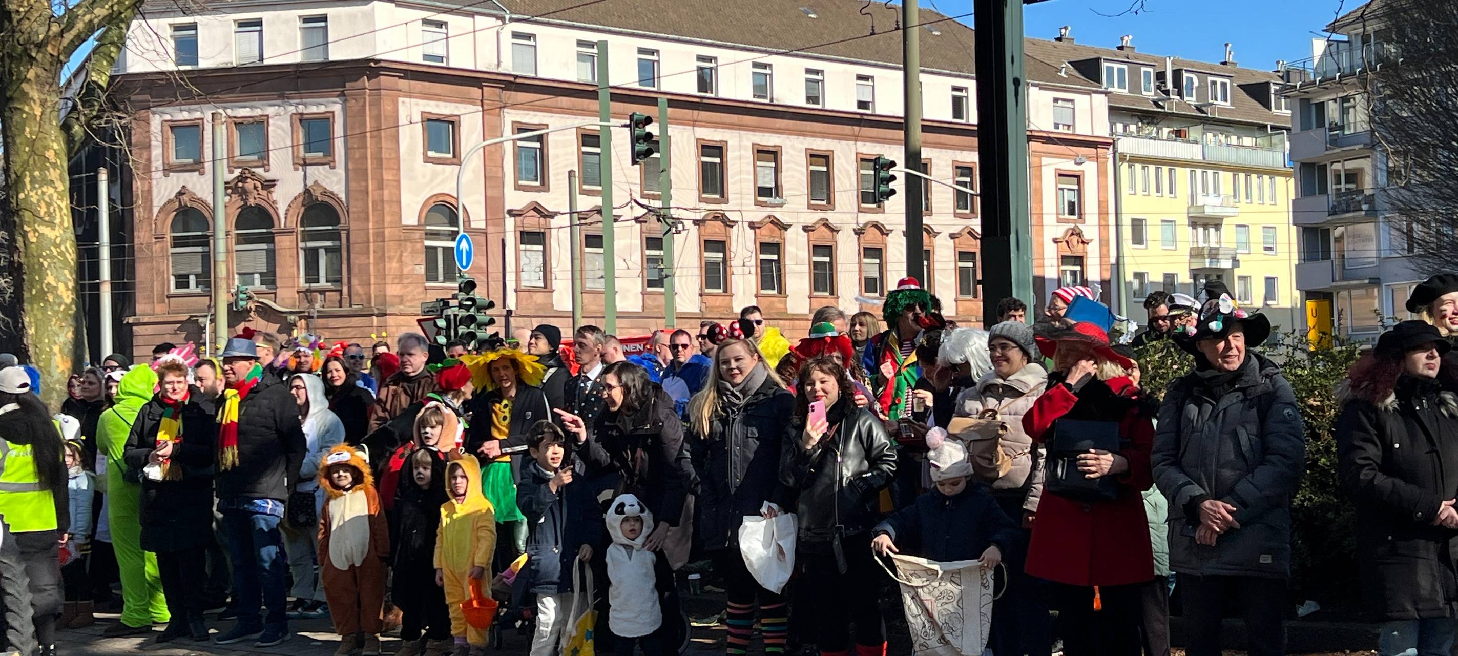 Bunt verkleidete Jecken warten gemeinsam auf den Rosenmontagsumzug.