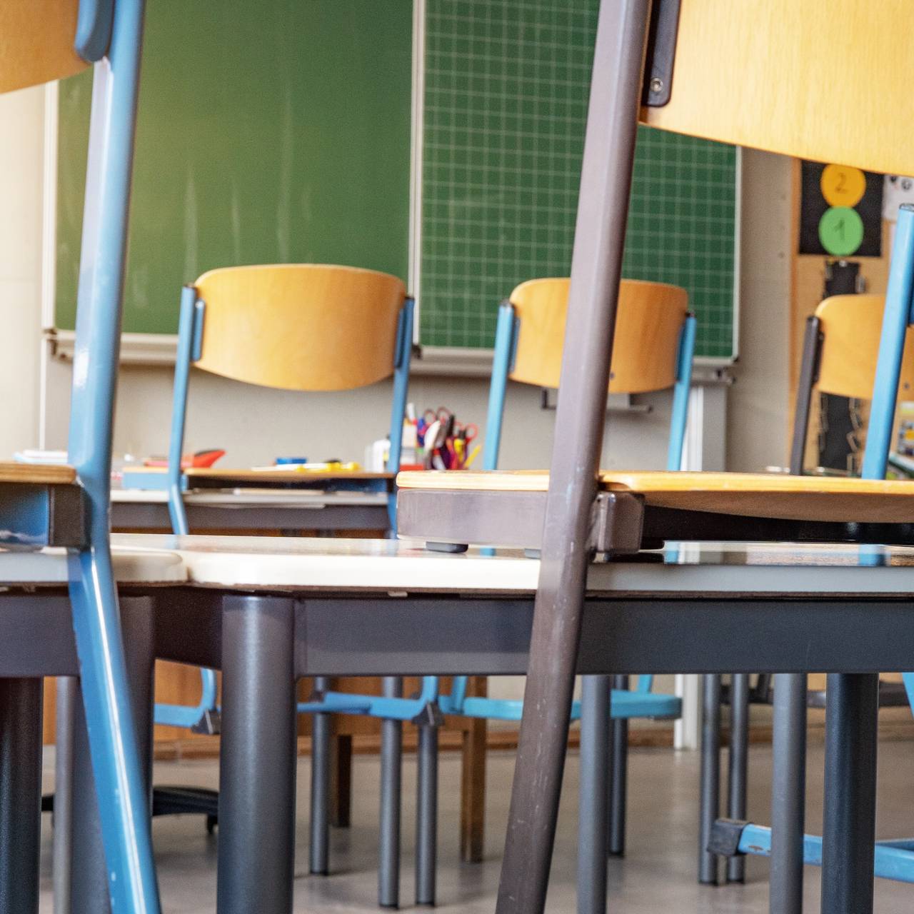 Leeres Klassenzimmer mit Stühlen auf den Tischen und leerer Tafel.