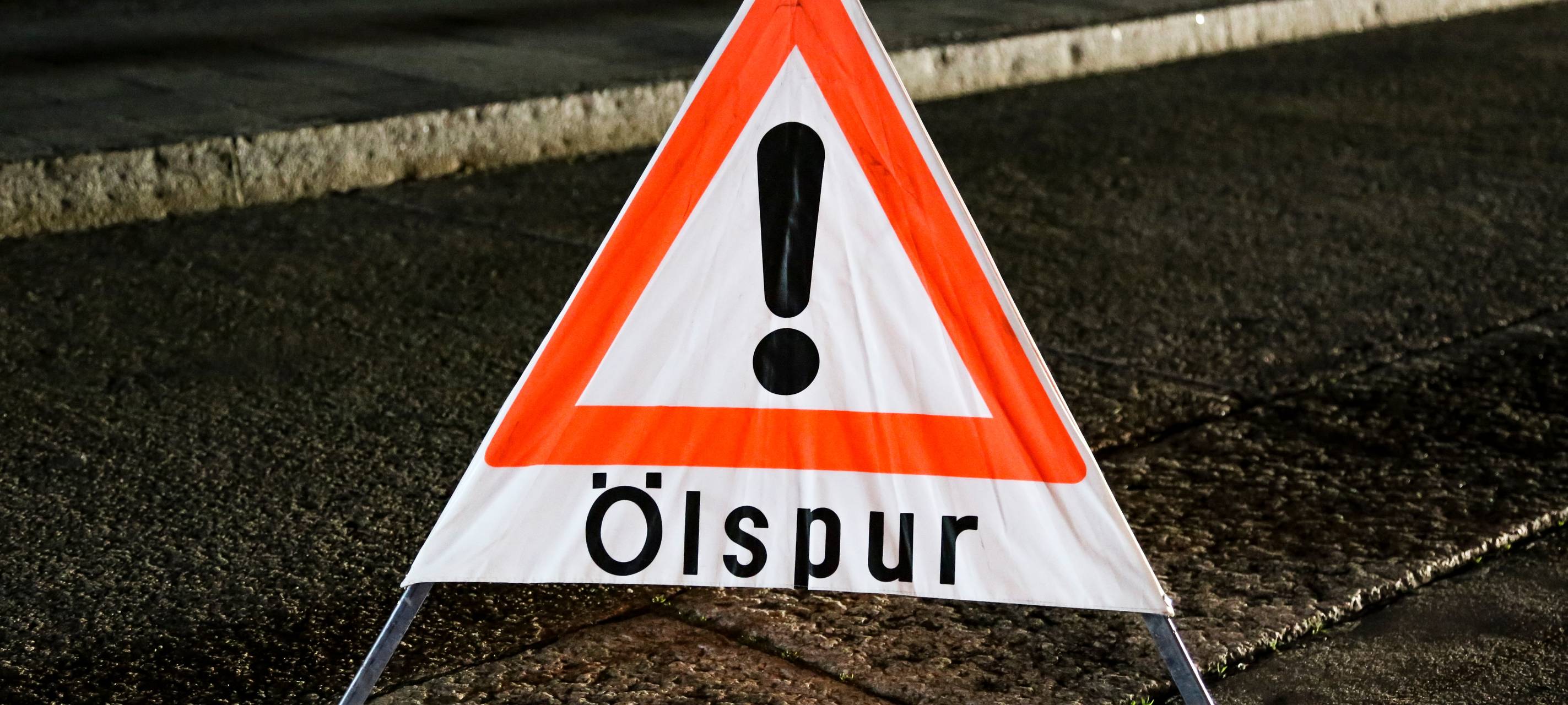 Ein Warnschild weist auf eine Ölspur hin.