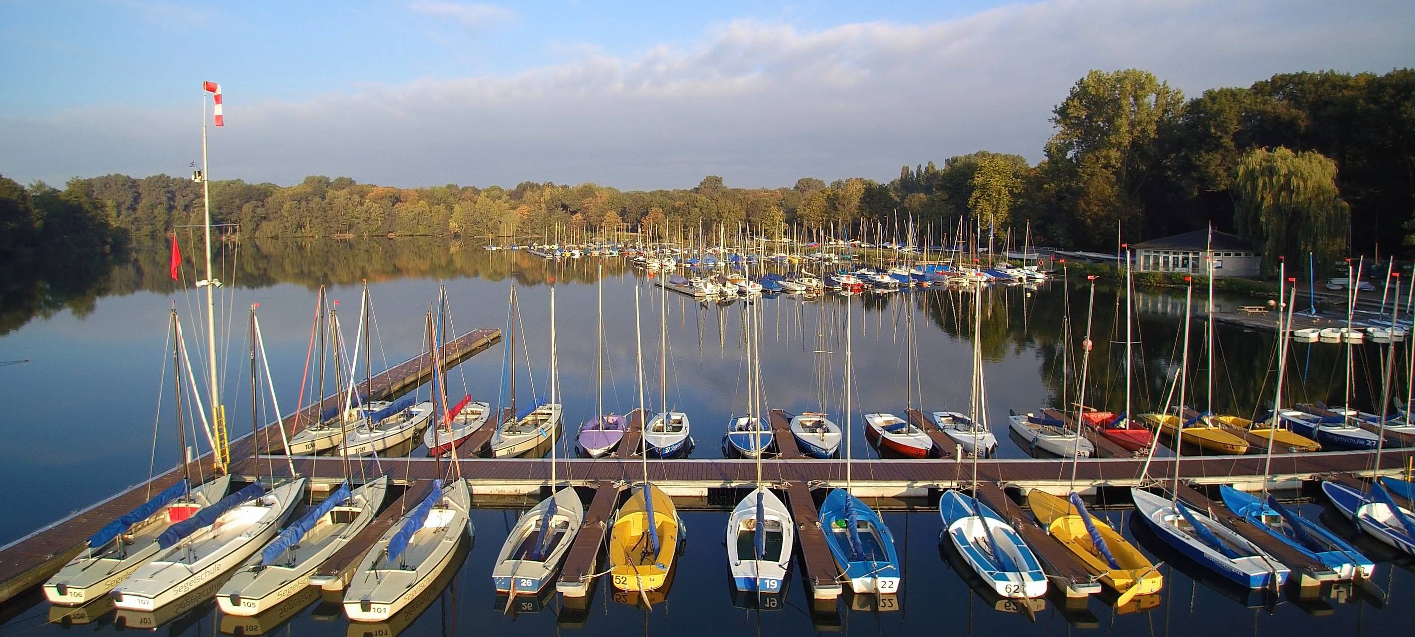Bunte Segelboote liegen an einem Steg im Unterbacher See. Jahreszeit: Spätsommer.