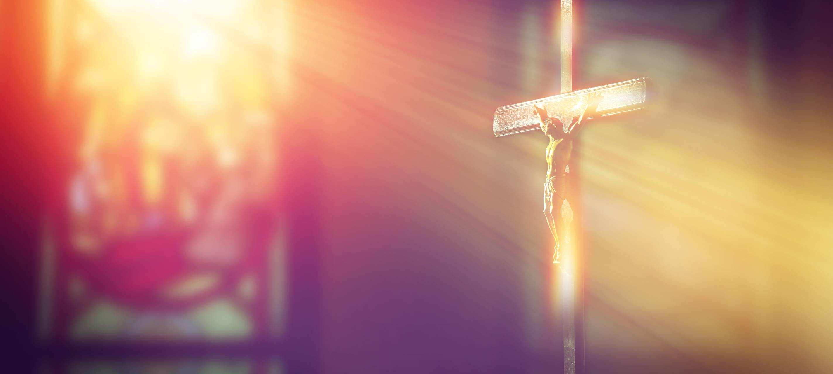 Kruzifix, Jesus am Kreuz in der Kirche mit Lichtstrahlen von Buntglasfenstern.